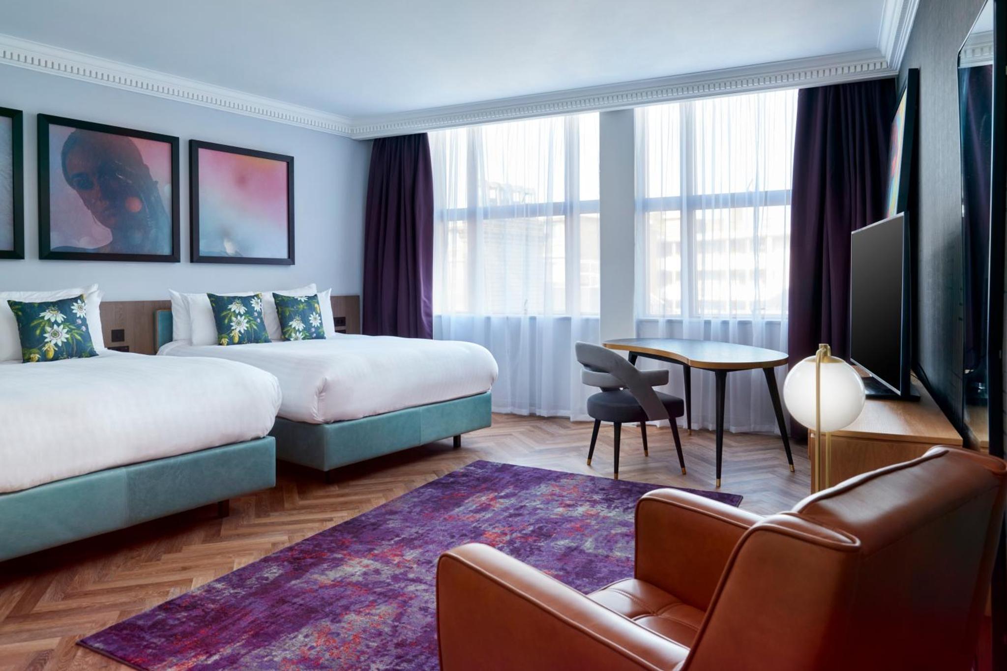 a hotel room with two beds and a table at NYX Hotel London Holborn by Leonardo Hotels in London