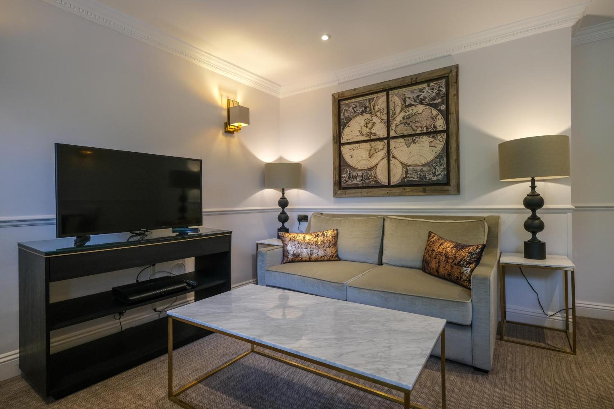 a living room with a couch and a flat screen tv at Collingham Serviced Apartments in London +22 photos