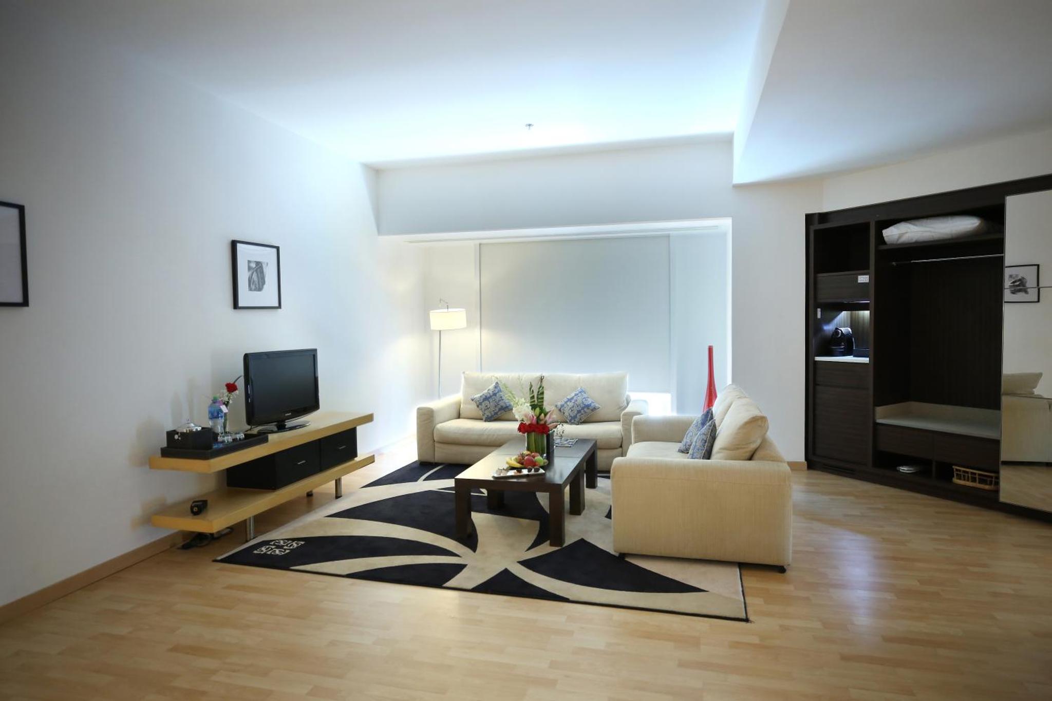 a living room with a couch and a tv at Asdal Boutique Hotel Seef in Manama