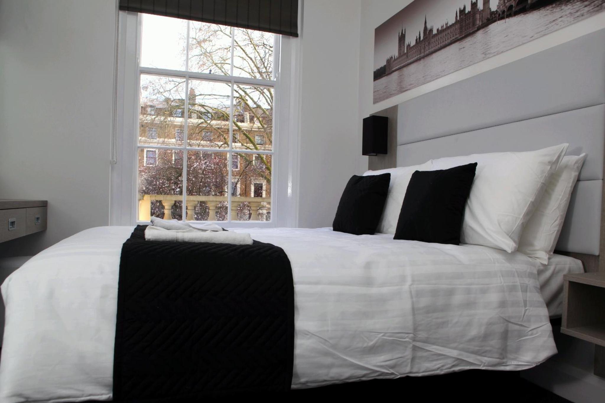 a white bed with black pillows and a window at The Omega Hotel in London +71 photos