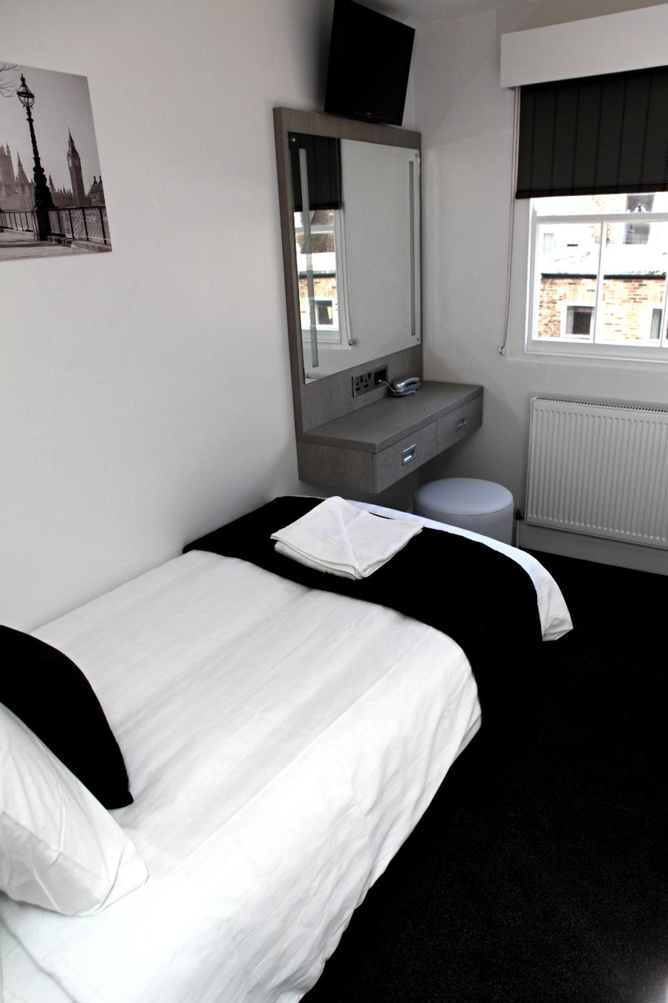 a bedroom with a large white bed and a mirror at The Omega Hotel in London