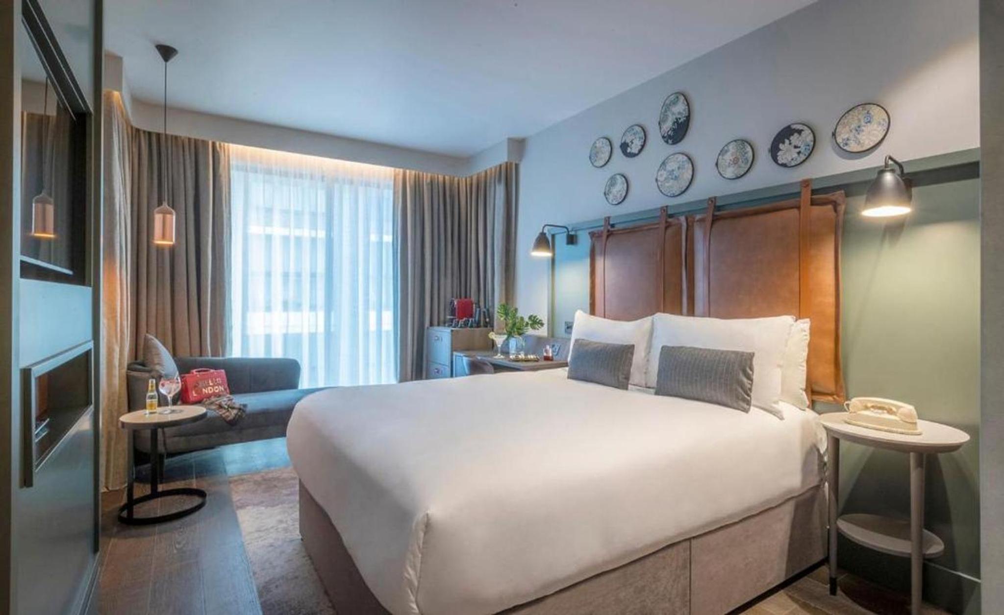 a bedroom with a large bed and a living room at Clayton Hotel City of London, Tower Bridge in London