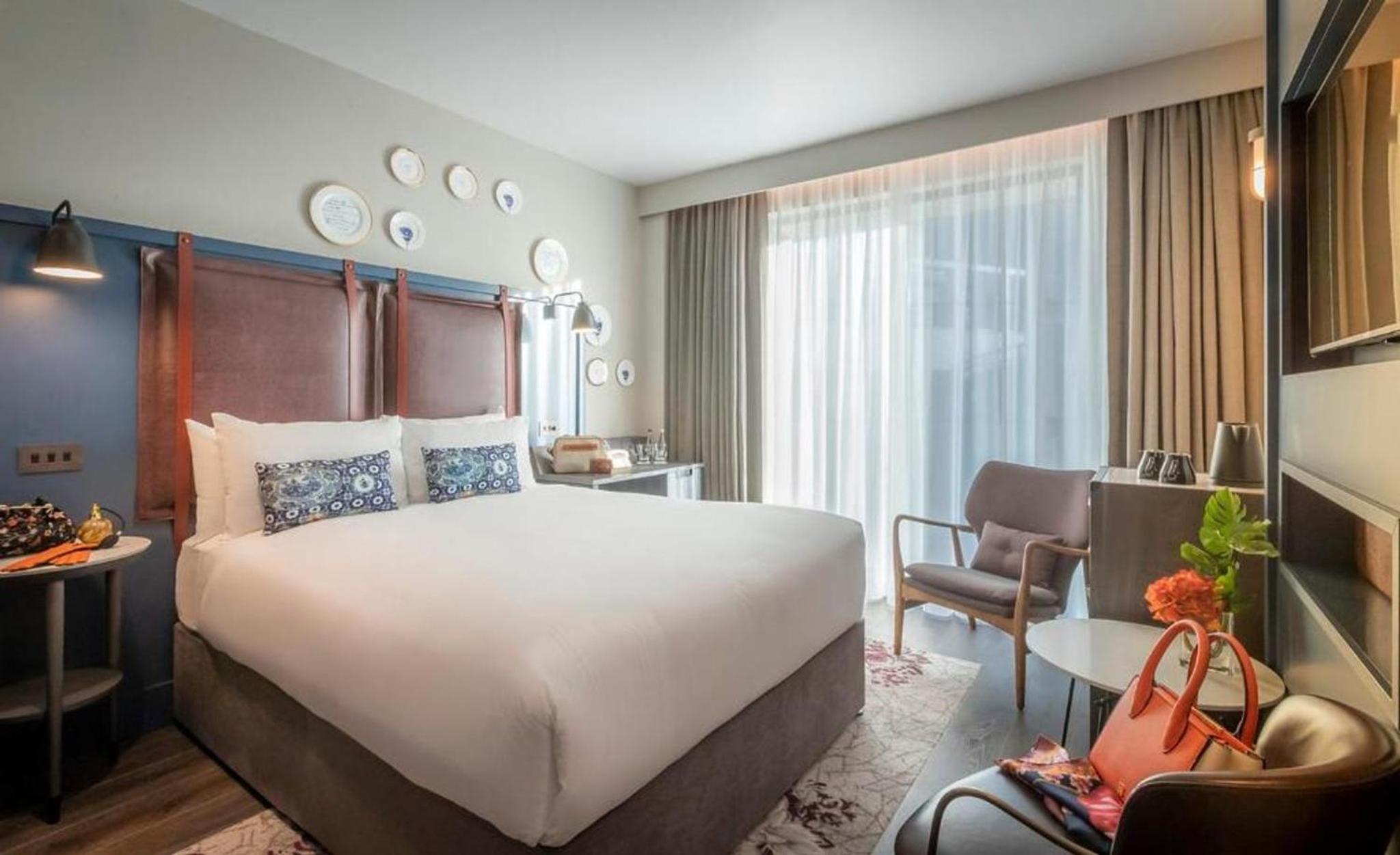 a hotel room with a large bed and a chair at Clayton Hotel City of London, Tower Bridge in London