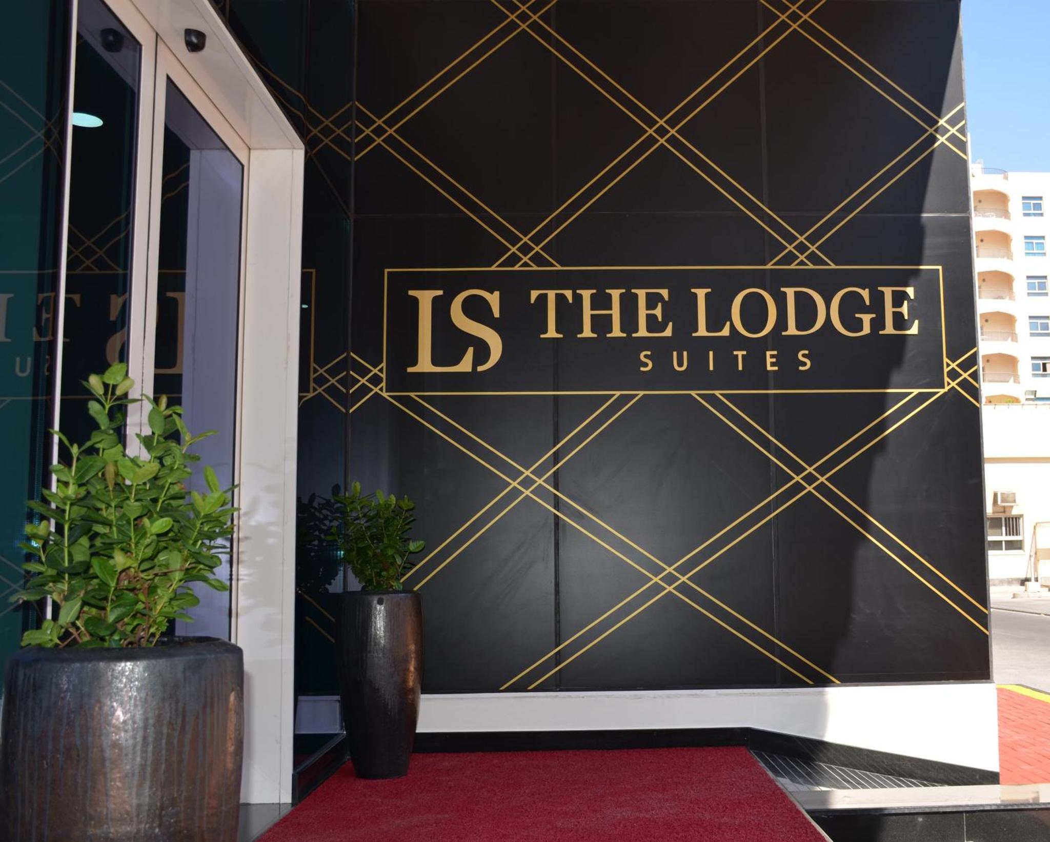 a black and gold wall with a sign that reads is the lodge suites at The Lodge Suites in Manama