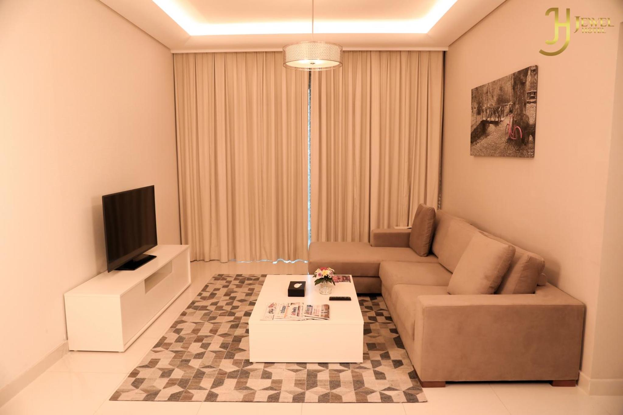 a living room with a couch and a tv at Sunday Luxury Downtown Adliya Formerly Jewel Hotel in Manama