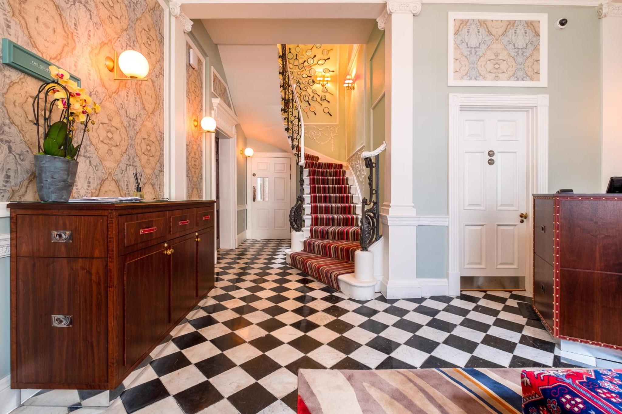 a hallway with a checkered floor and a staircase at Home House Studio in London
