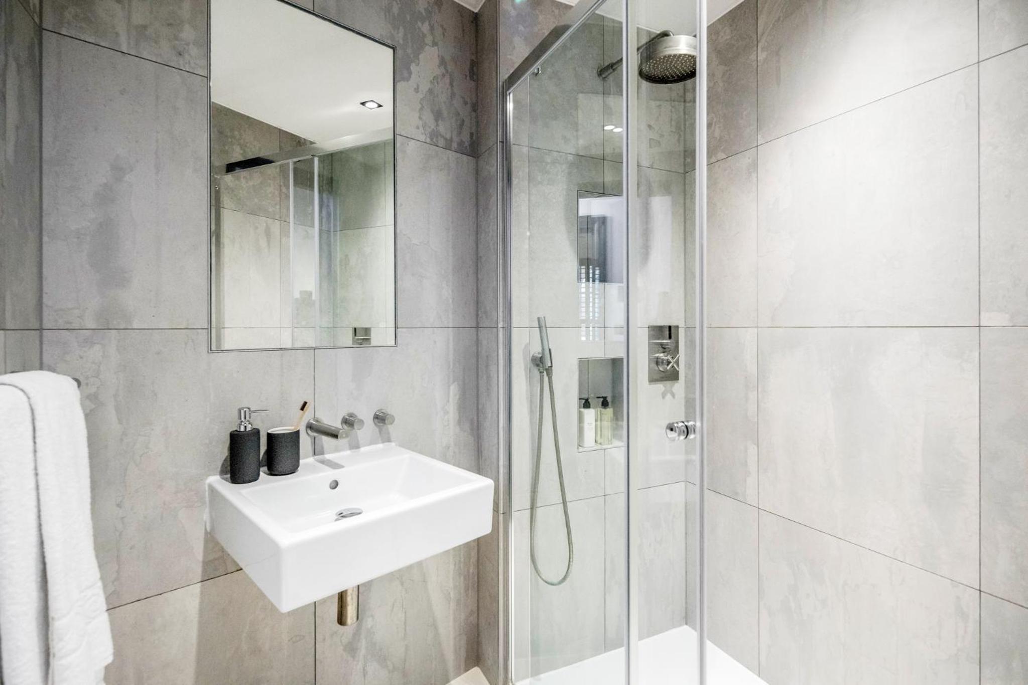 a white bathroom with a sink and a shower at Stay Kula London - Covent Garden Garrick St in London