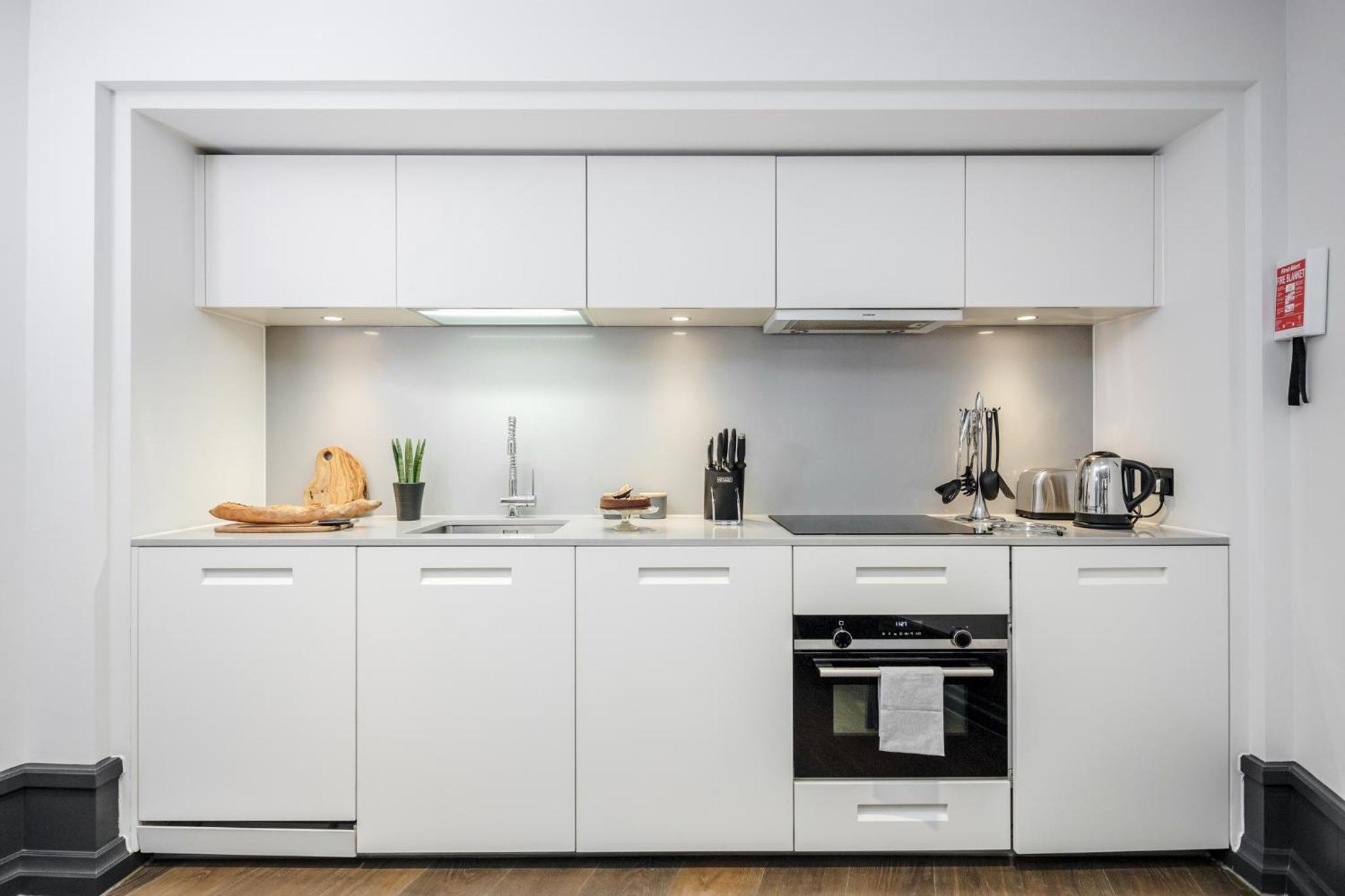 a white kitchen with white cabinets and appliances at Stay Kula London - Covent Garden Garrick St in London +102 photos