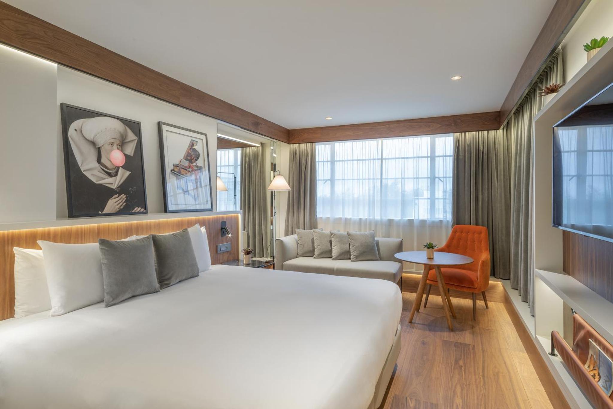 a bedroom with a large bed and a living room at Melia White House Hotel in London