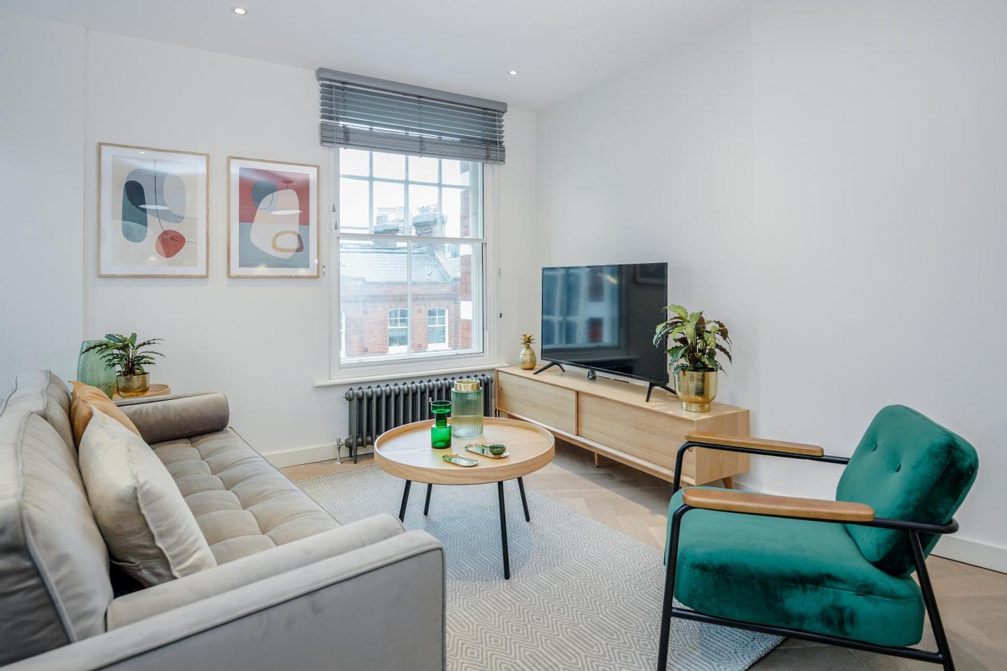 a living room with a couch and a table and a tv at Stay Kula London - Fitzrovia Newman St in London