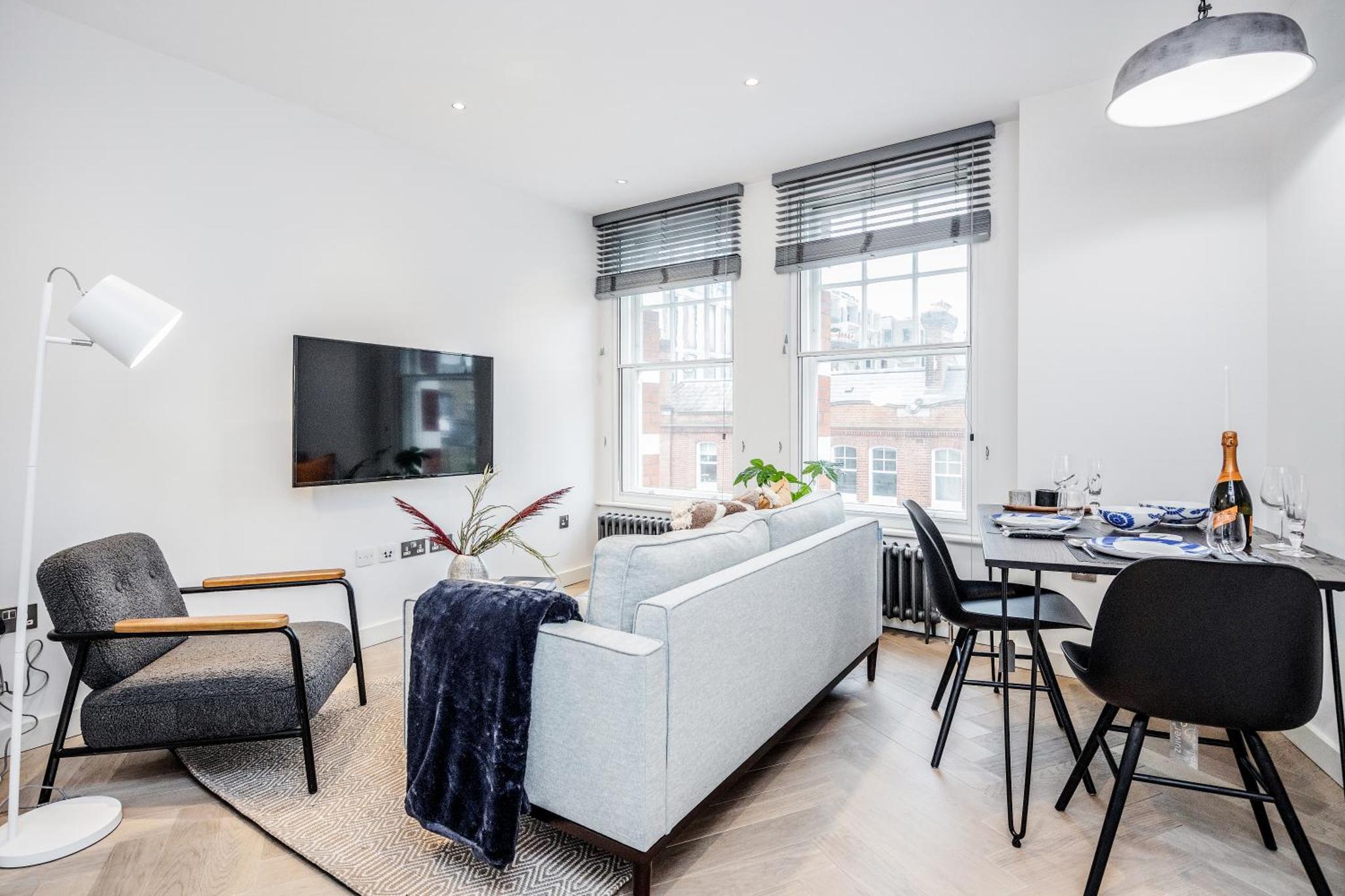 a living room with a couch and a table with chairs at Stay Kula London - Fitzrovia Newman St in London +30 photos
