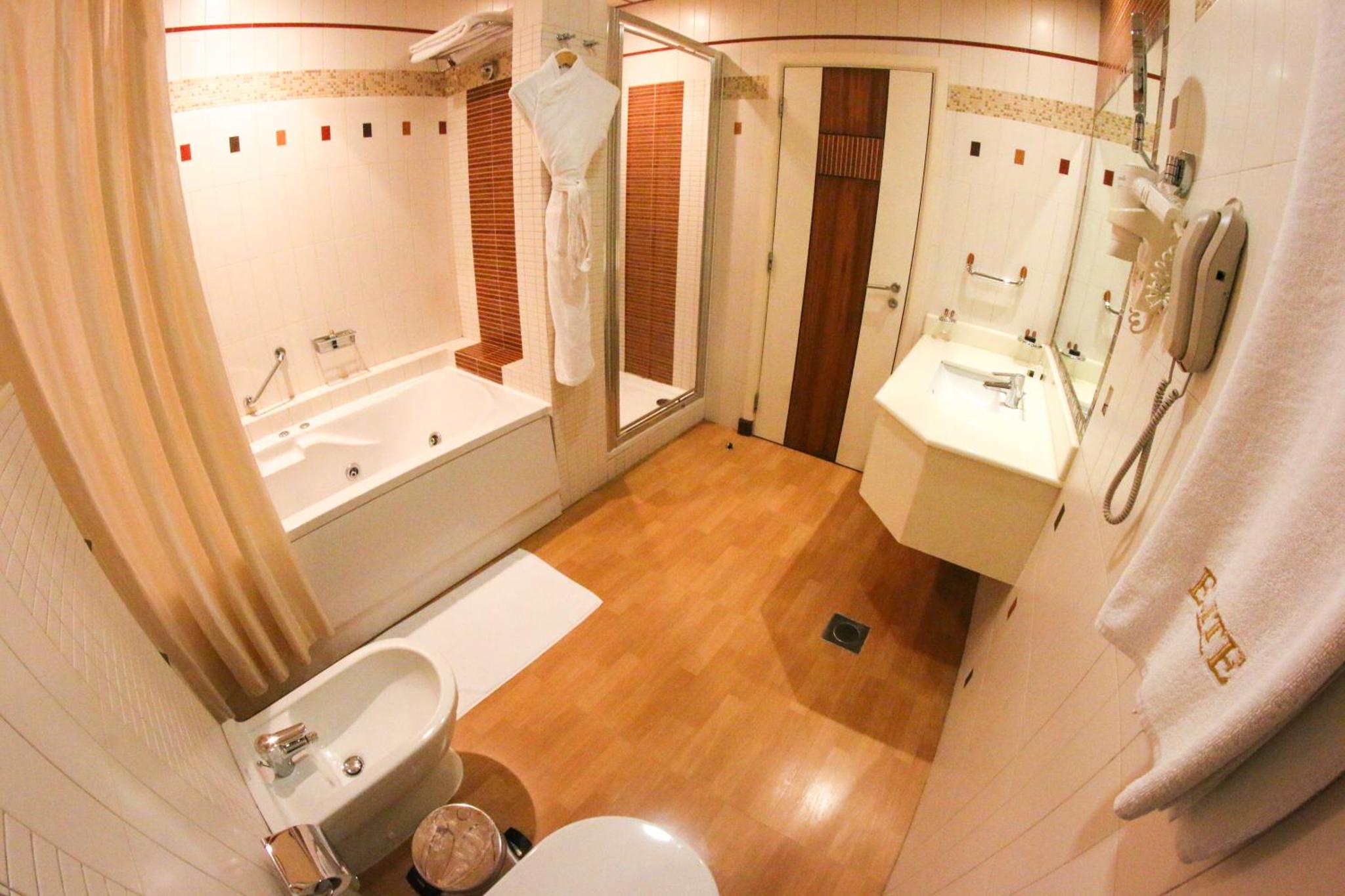 a bathroom with a toilet and a tub and a sink at City Center Hotel in Manama +24 photos