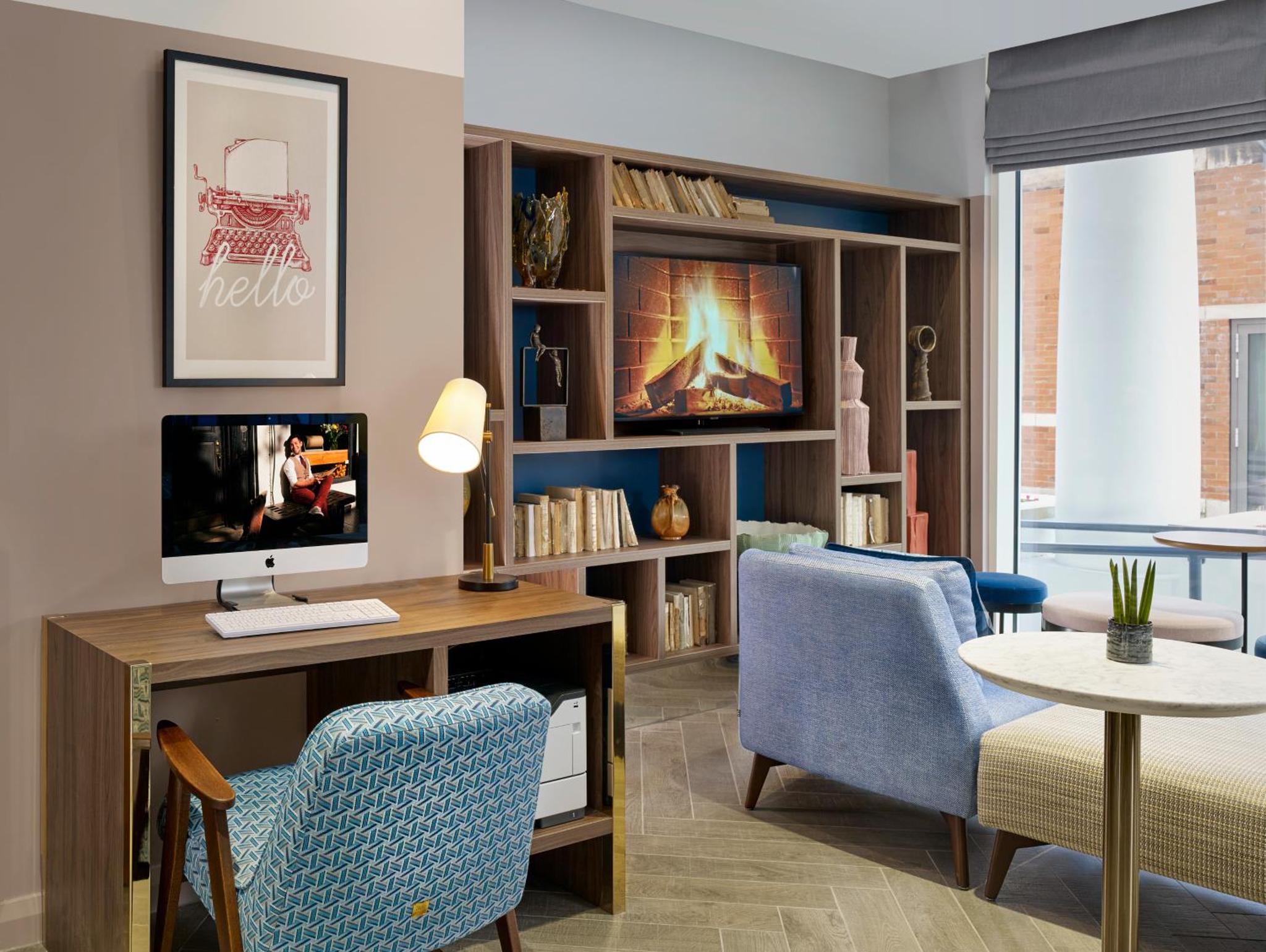 a living room with a tv and a desk and chairs at Citadines Islington London in London +18 photos