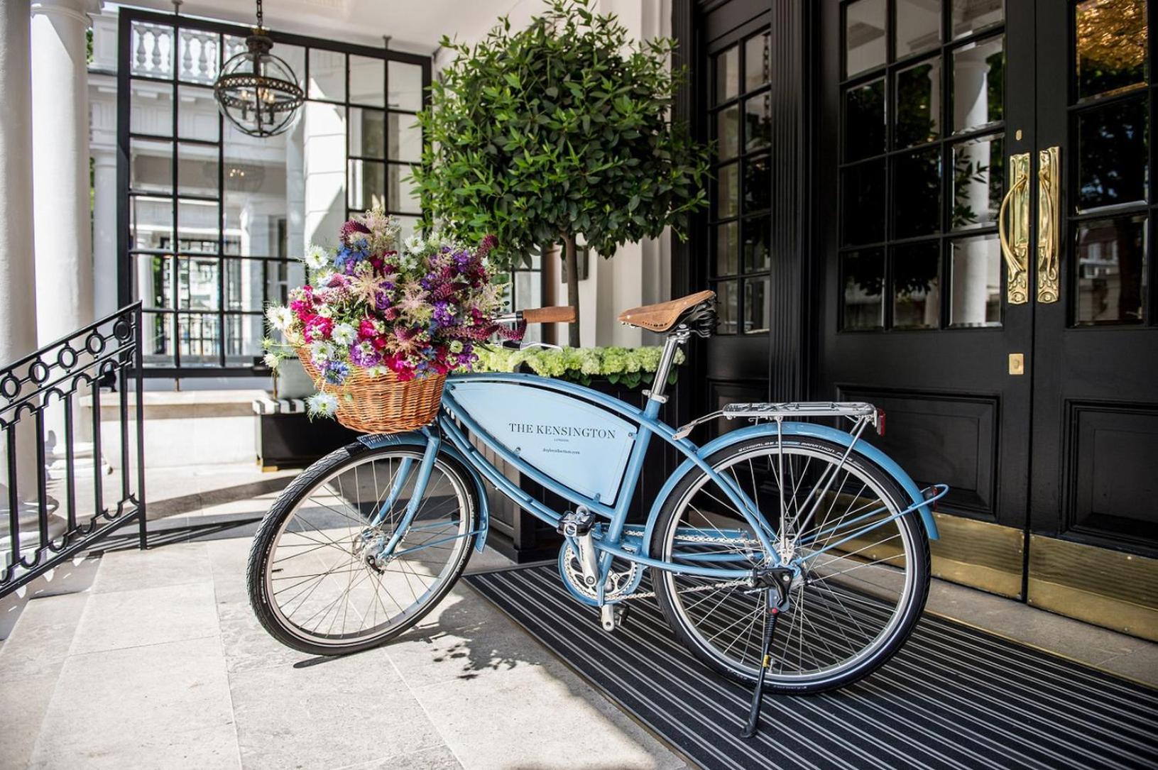 a blue bike parked outside of a building with flowers at The Kensington Hotel in London