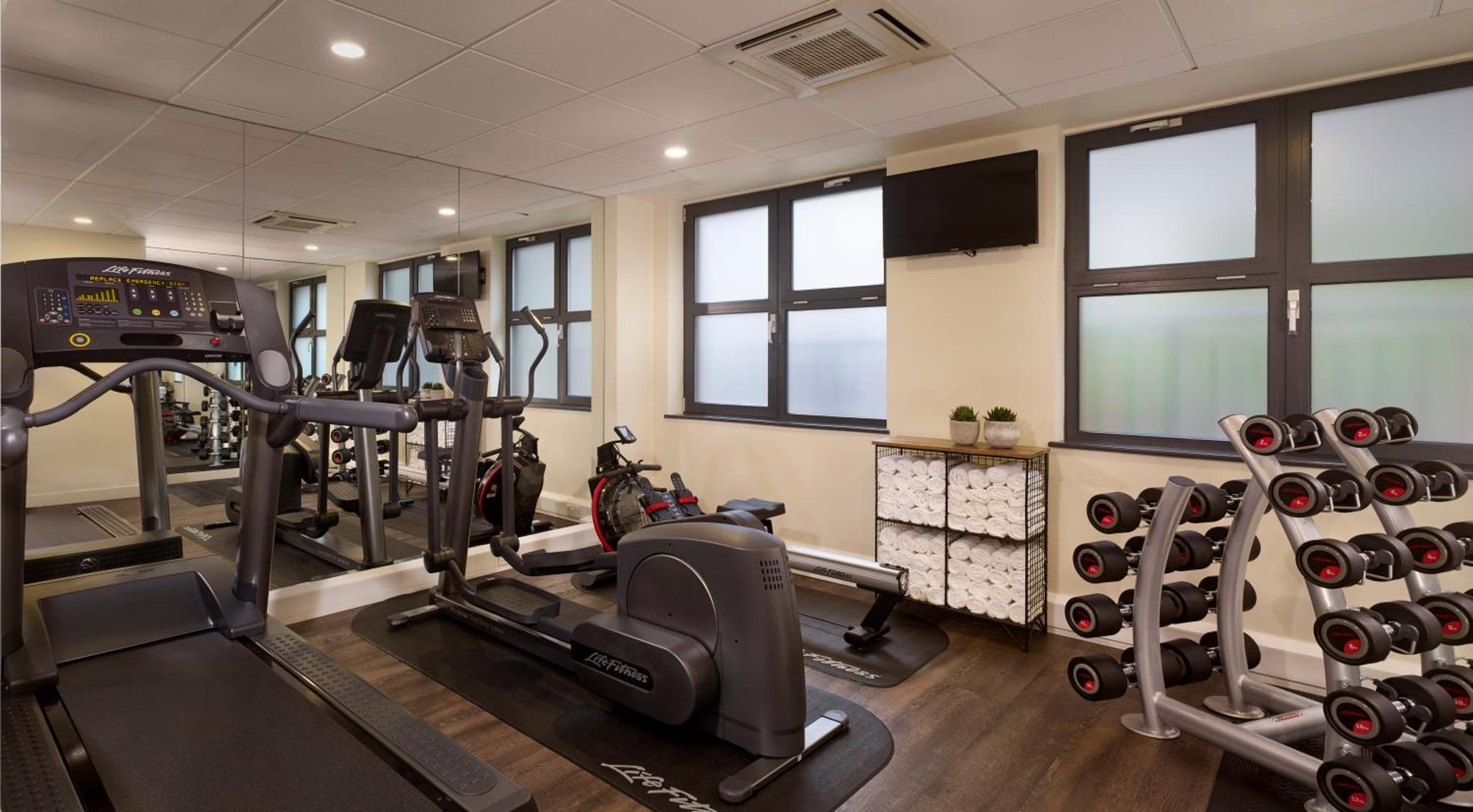 a gym with two treadmills and two machines at Citadines Barbican London in London