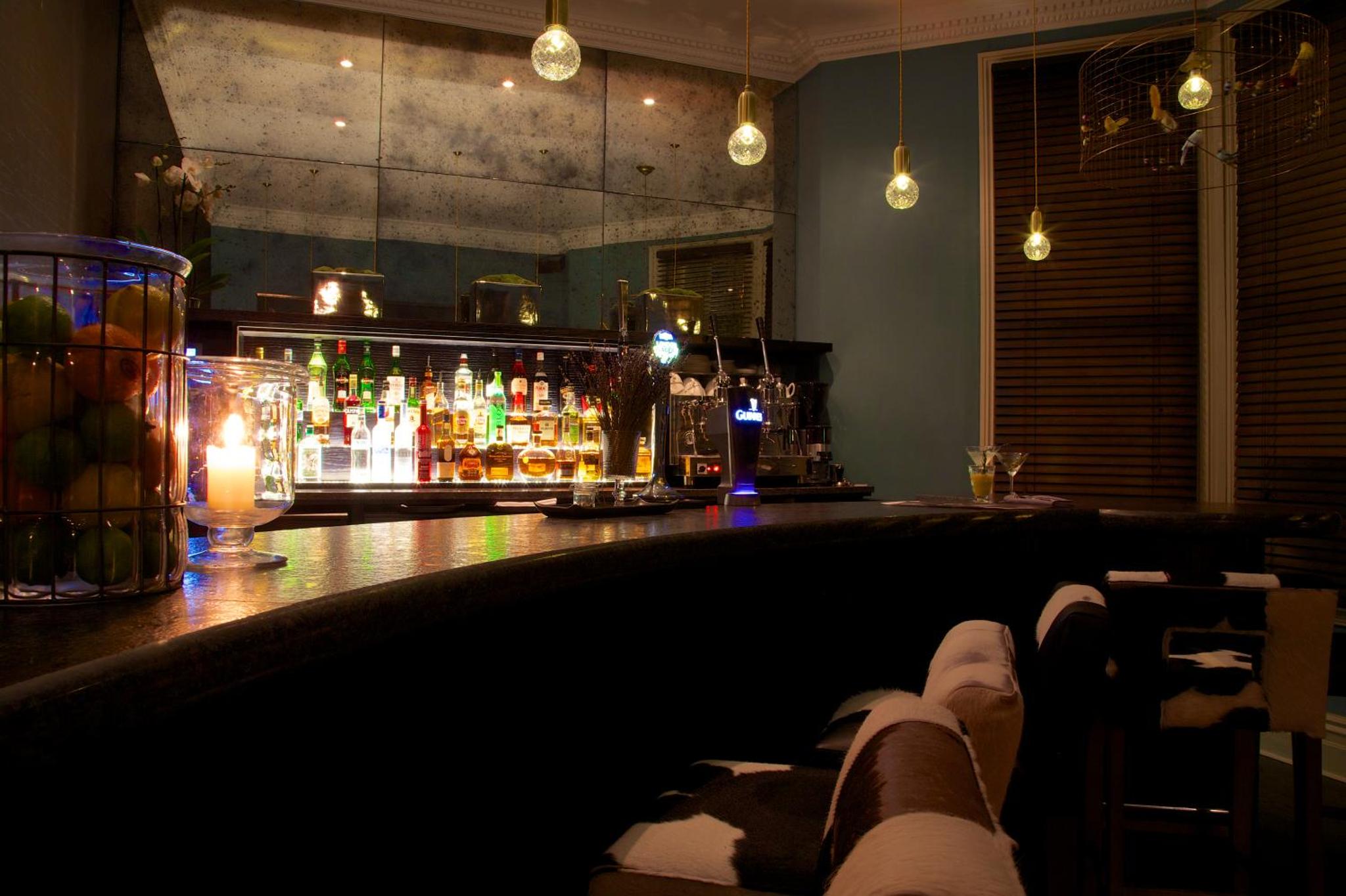a bar with a counter with a lot of drinks at The Lodge Hotel - Putney in London