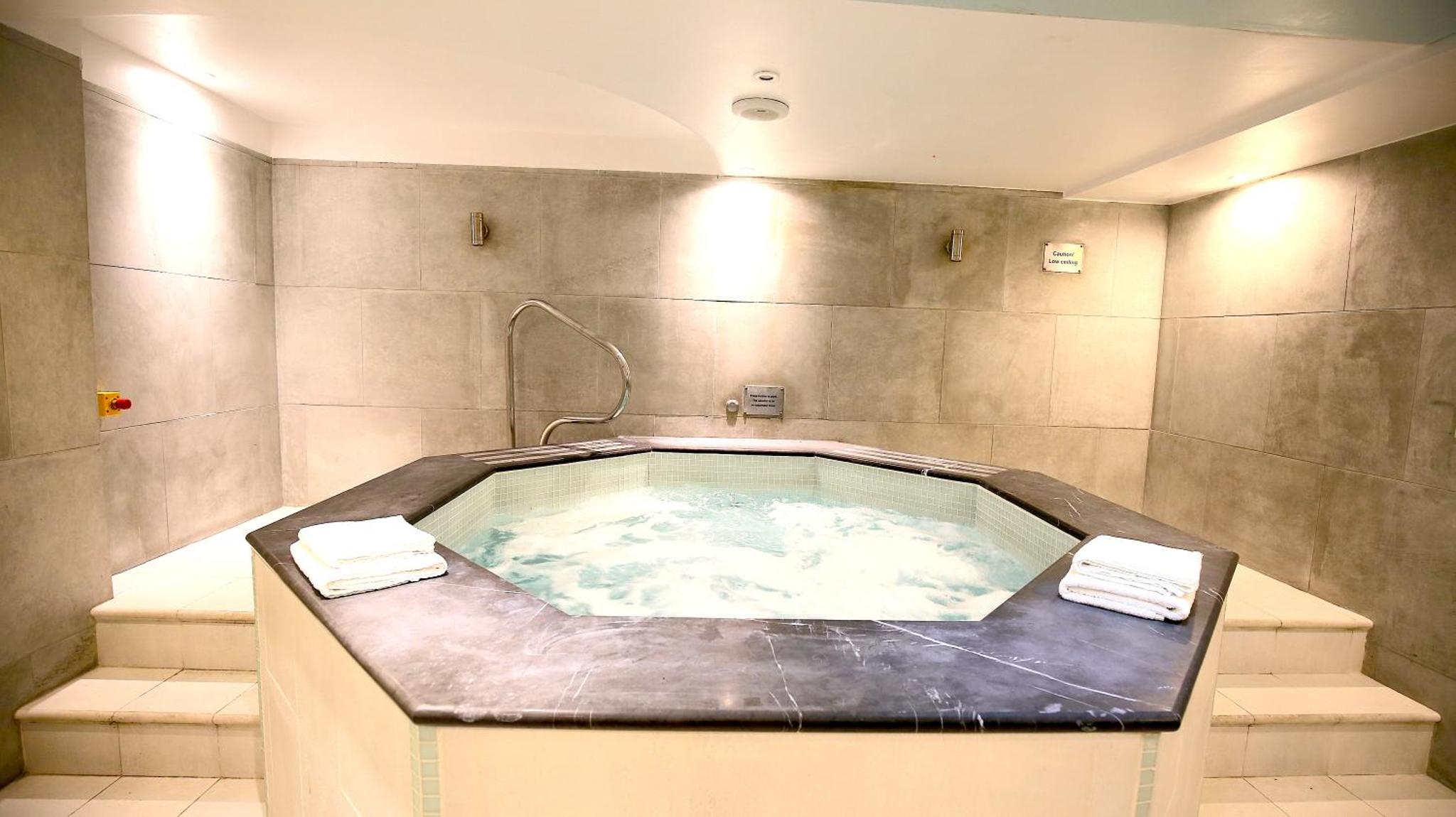 a jacuzzi tub in a bathroom with two towels at Roland House in London