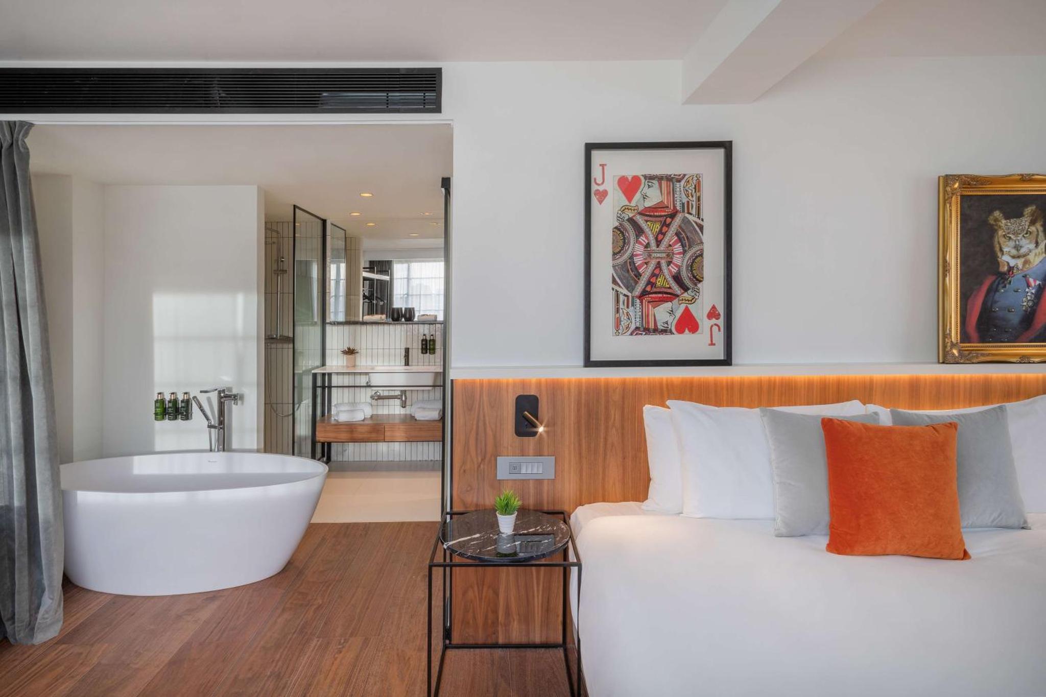 a bedroom with a tub and a bed and a bathroom at Melia White House Hotel in London