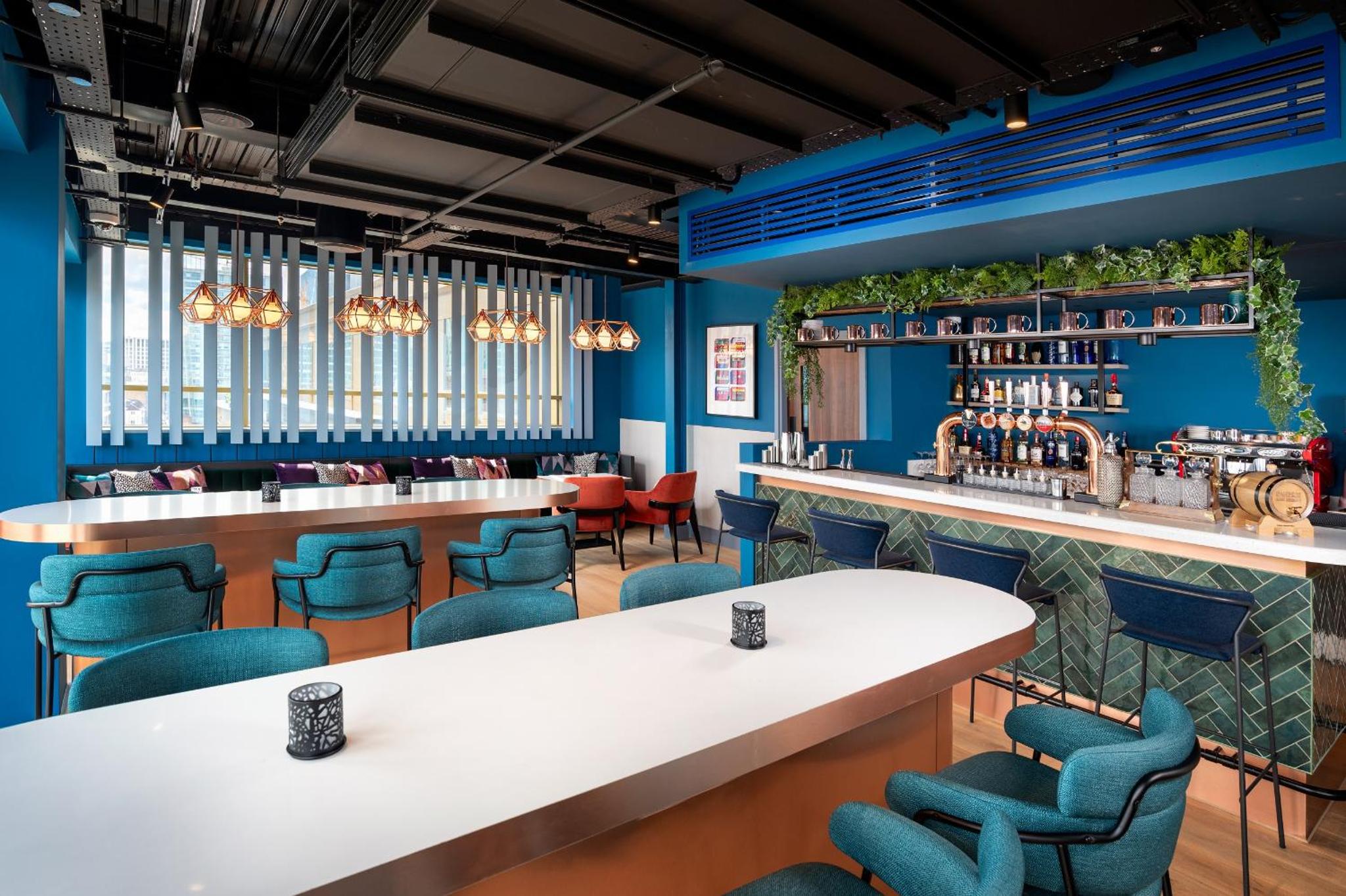 a restaurant with blue walls and tables and blue chairs at Hyatt Place London City East in London