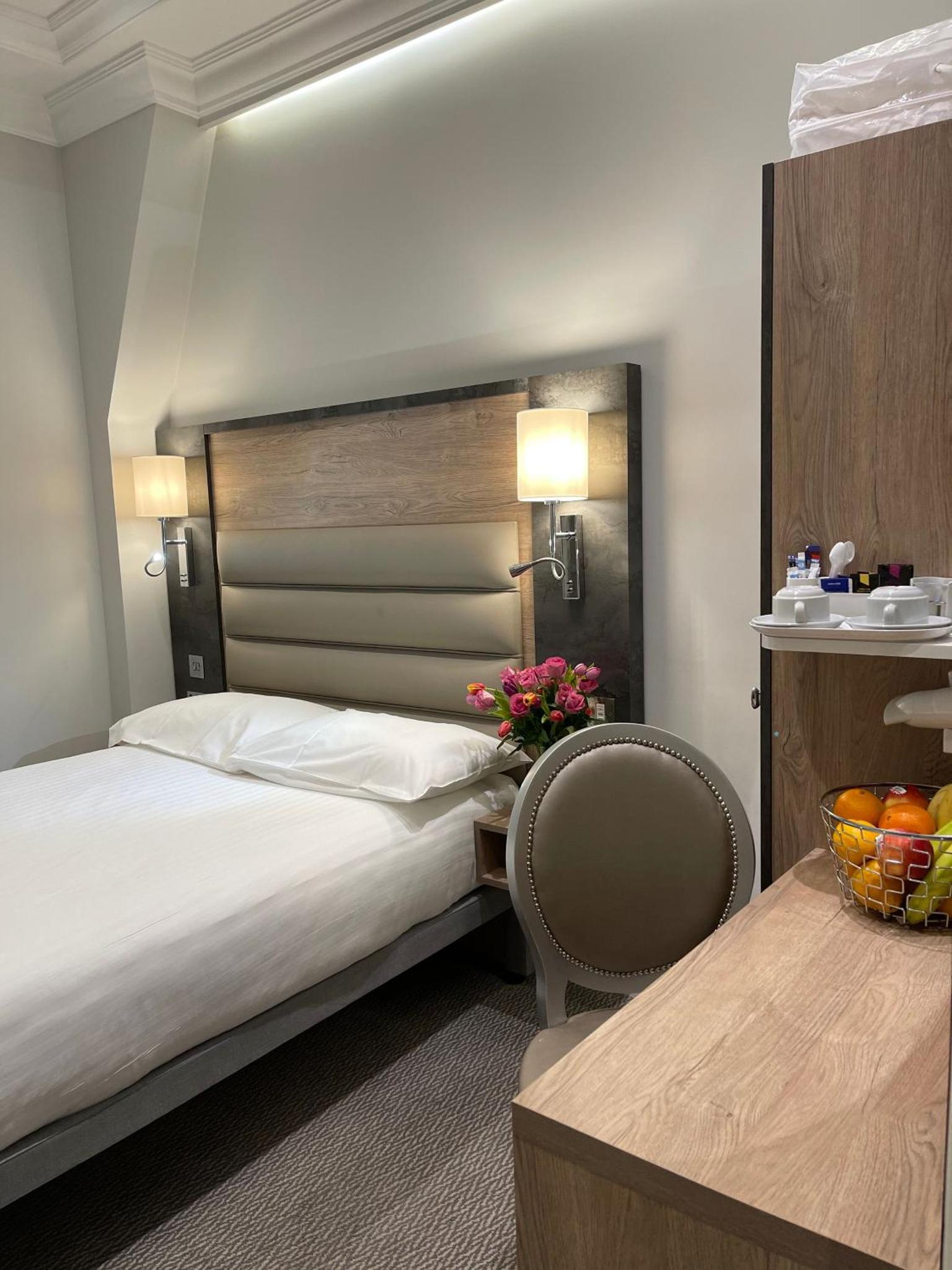 a bedroom with a bed and a table with a bowl of fruit at Best Western Buckingham Palace Rd in London