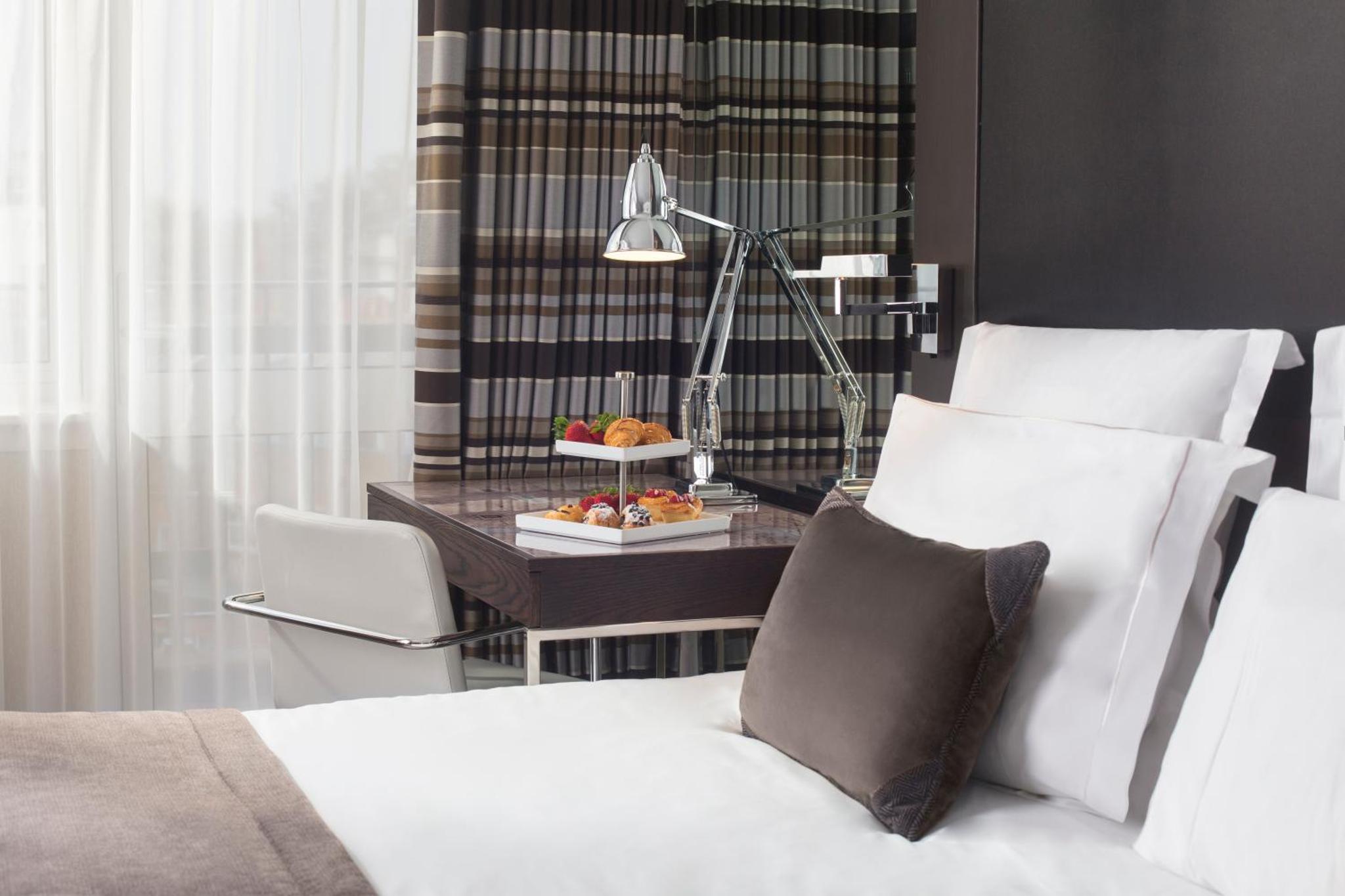 a bedroom with a bed and a table with a plate of food at The Lowndes London - A Jumeirah Partner Hotel in London