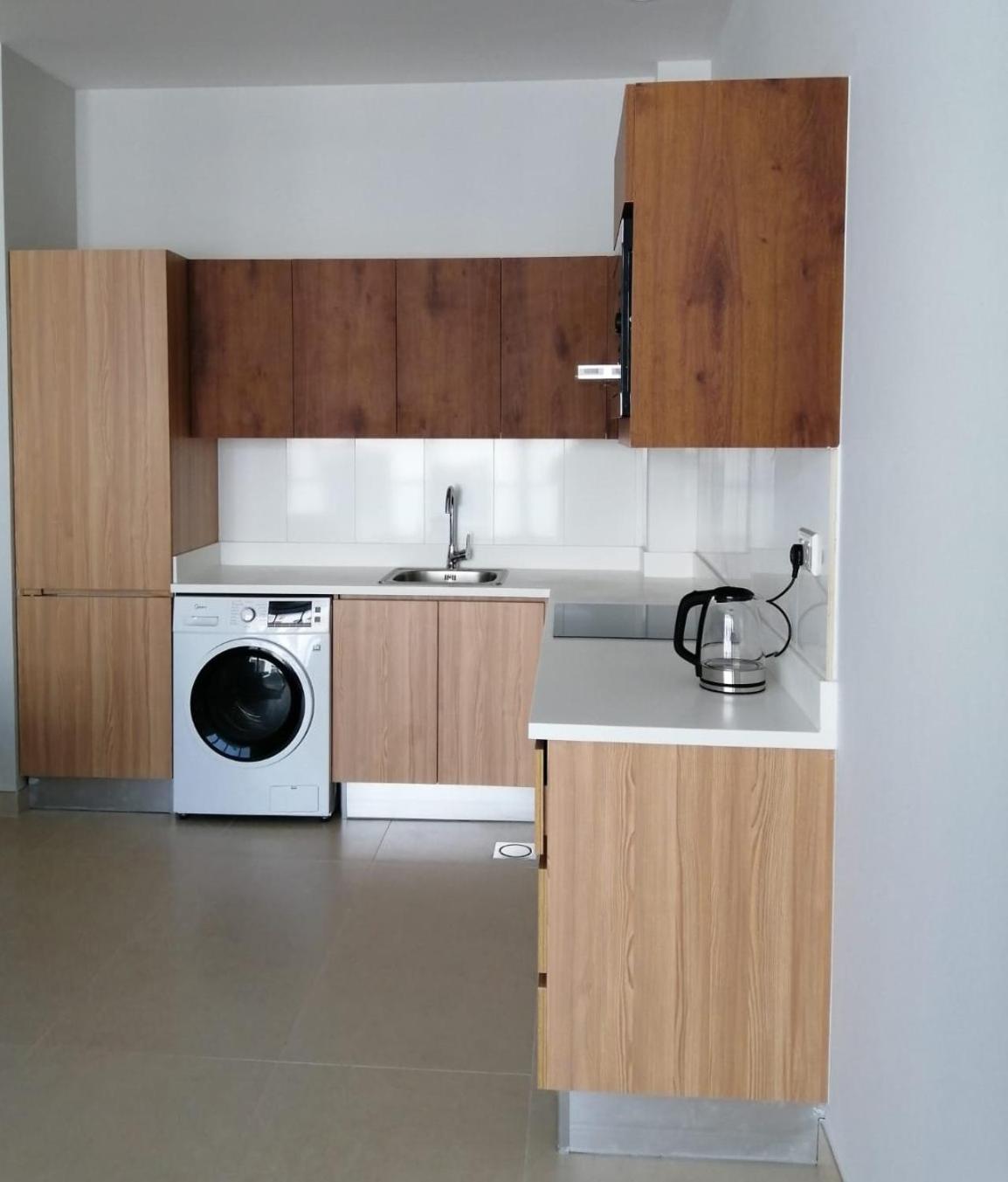 a kitchen with a sink and a washing machine at JOOD RESIDENCE in Seef