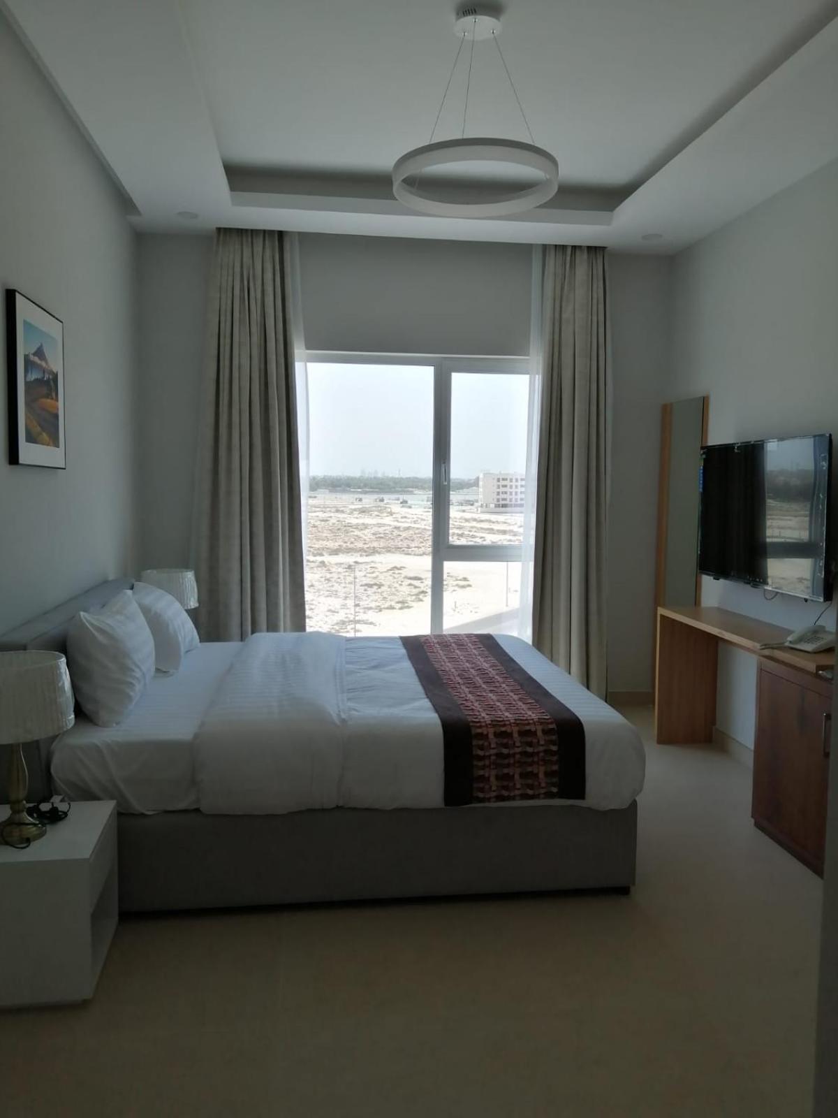 a bedroom with a bed and a large window at JOOD RESIDENCE in Seef +54 photos