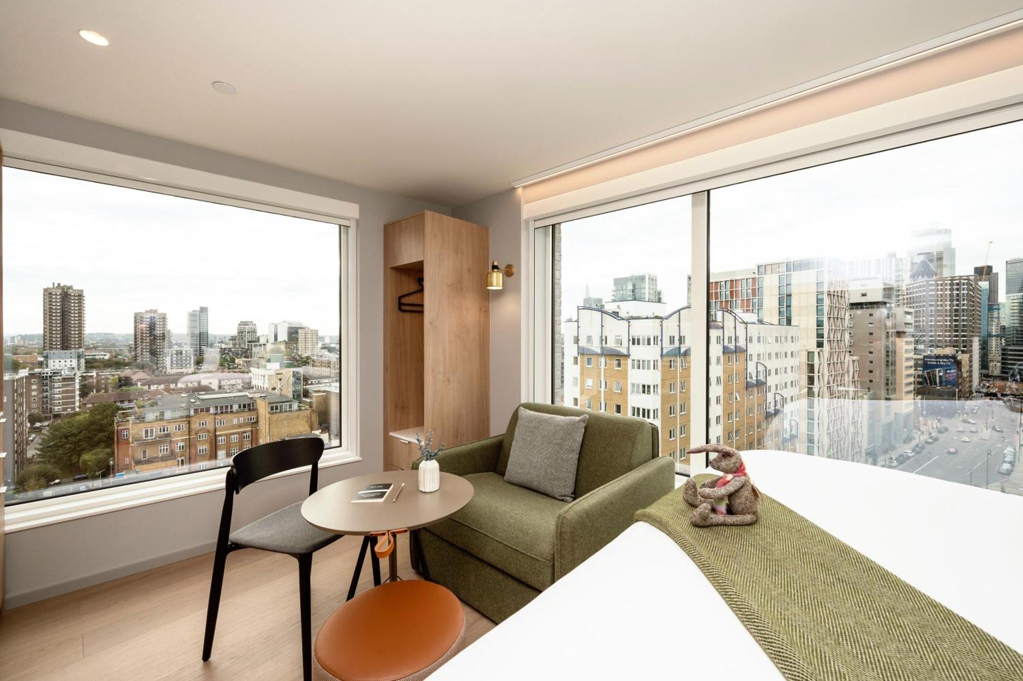 a room with a large window with a chair and a table at Wilde Aparthotels London Aldgate Tower Bridge in London
