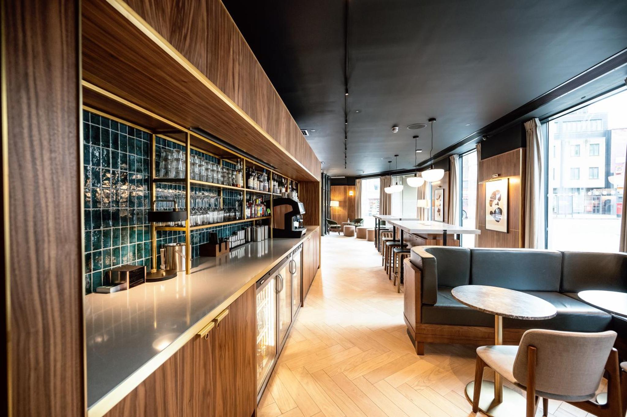a restaurant with a bar with chairs and tables at Wilde Aparthotels London Aldgate Tower Bridge in London