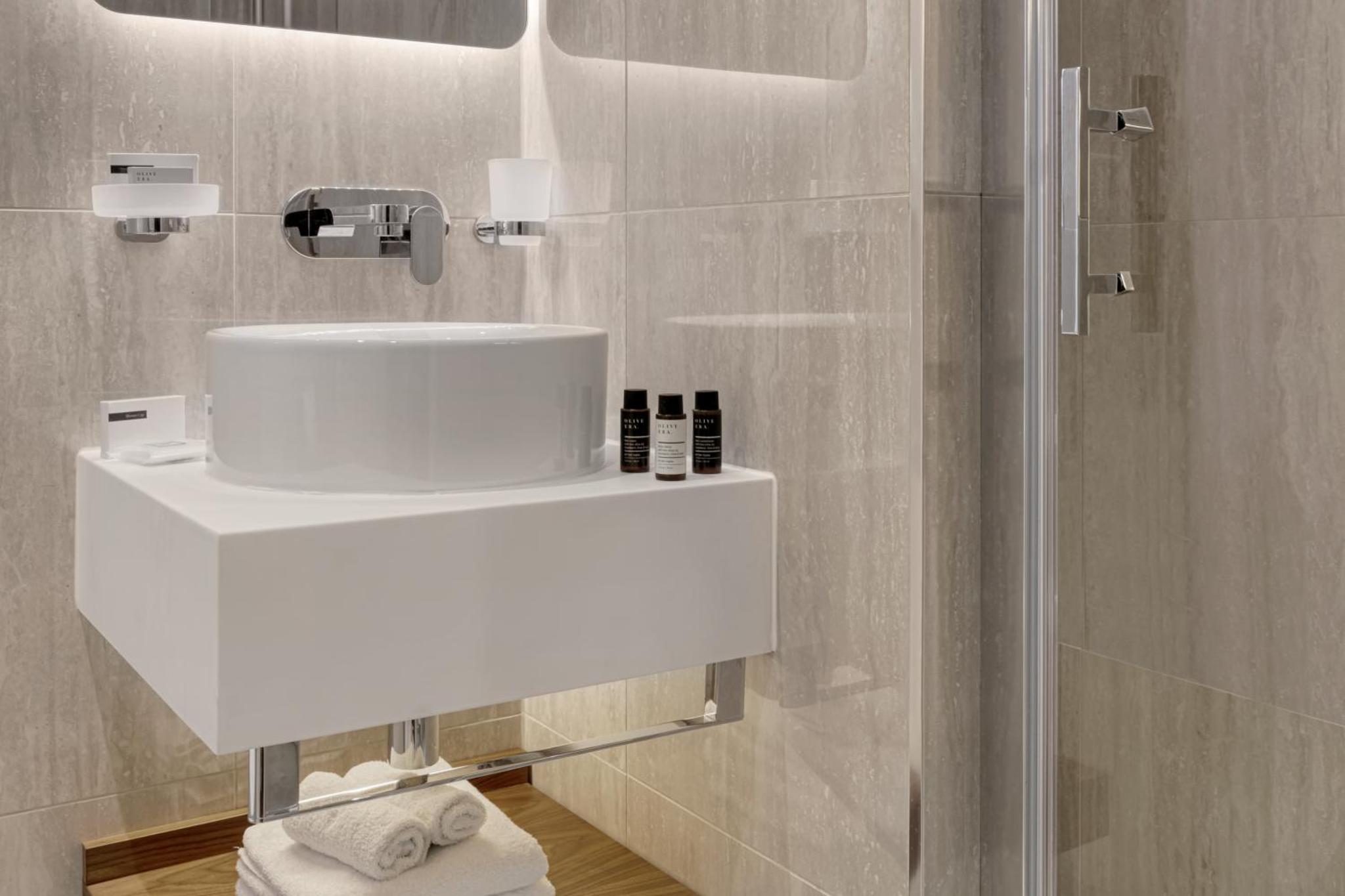 a bathroom with a white sink and a shower at The Queens Gate Hotel in London