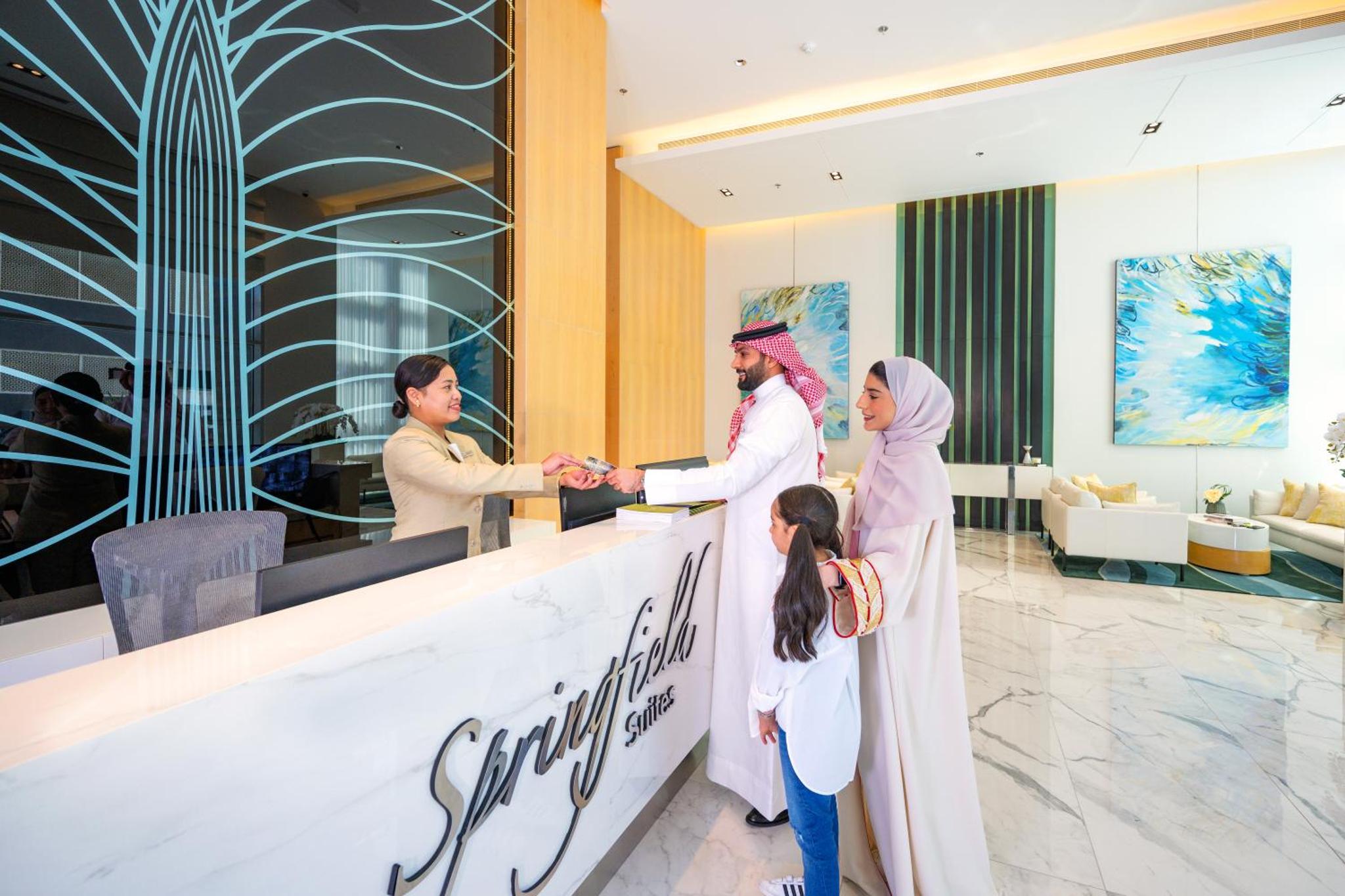 a bride and groom shaking hands at a counter in a hotel lobby at Springfield Suites in Seef +27 photos