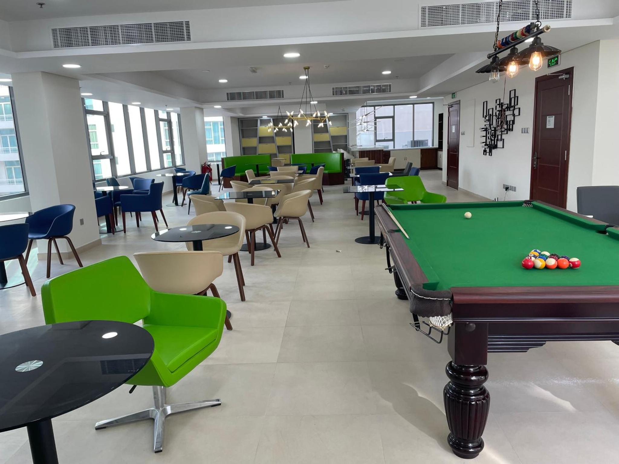 a billiard room with a pool table and chairs at The Apple Residence in Juffair