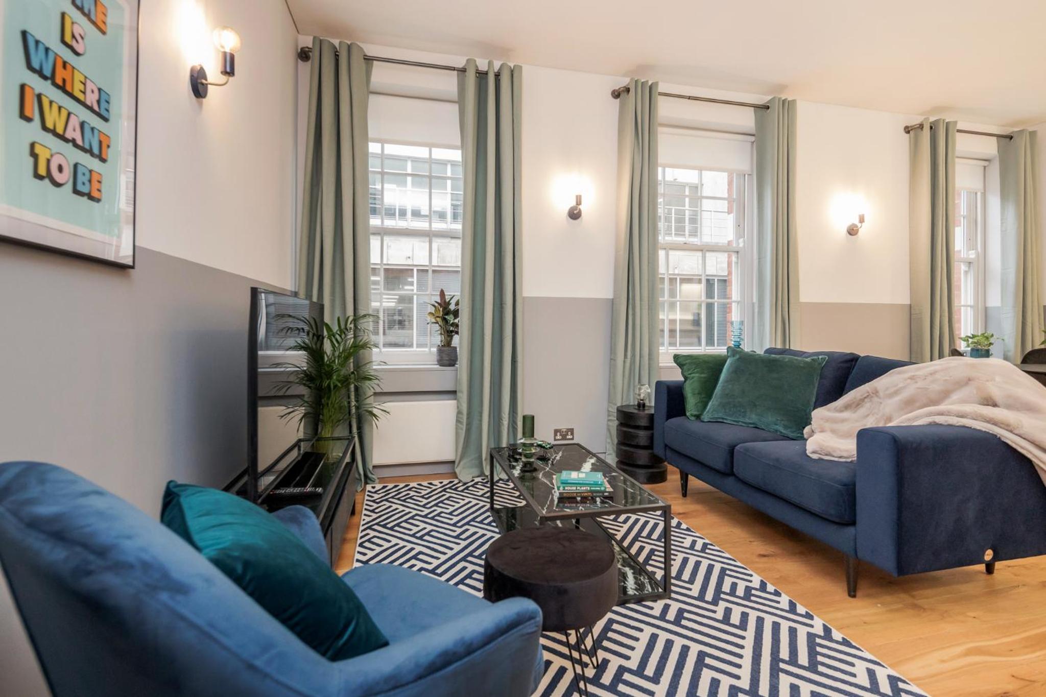 a living room with two blue couches and a rug at Stay Kula London - Holborn in London +103 photos