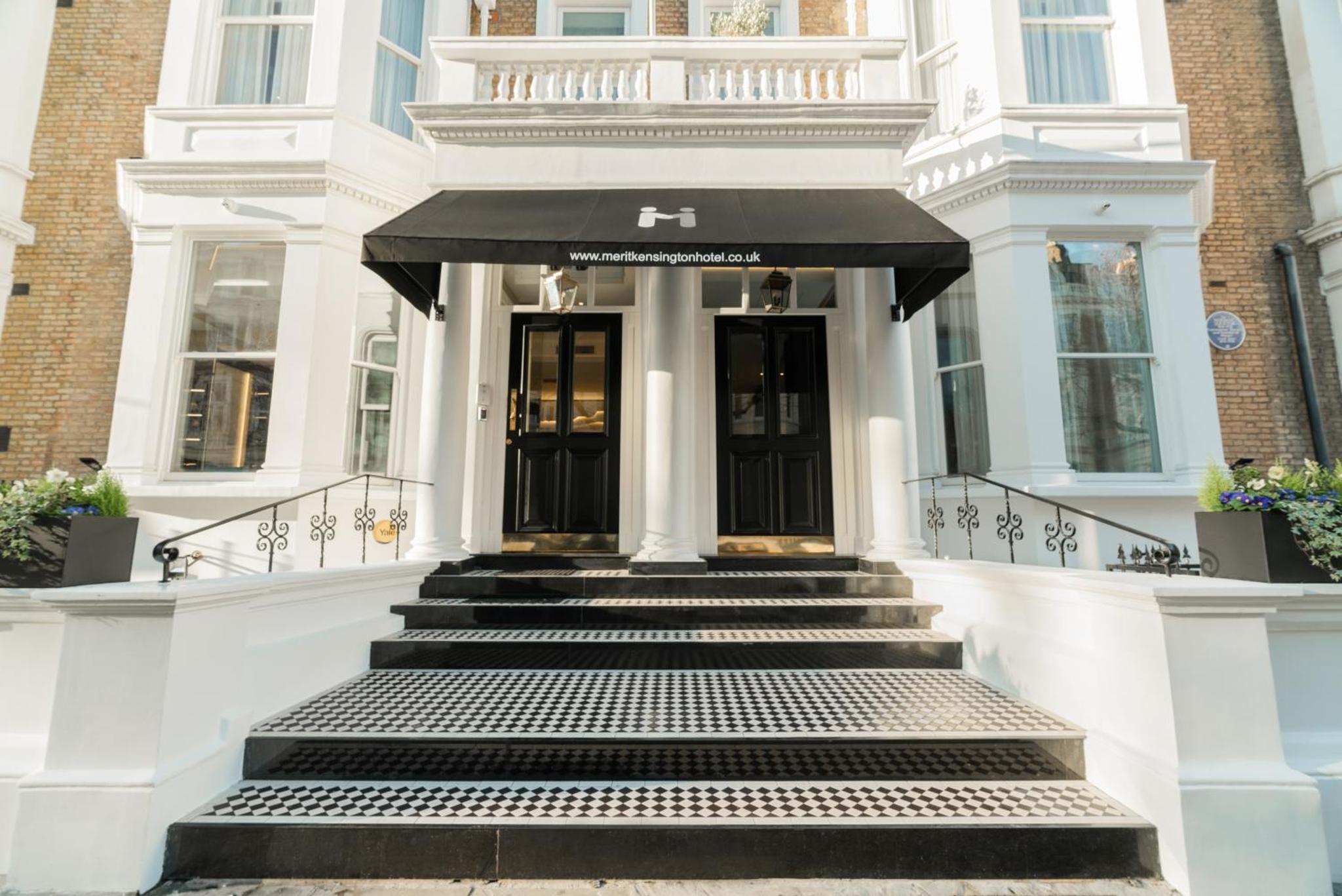a white house with a black awning at Merit Kensington Hotel in London