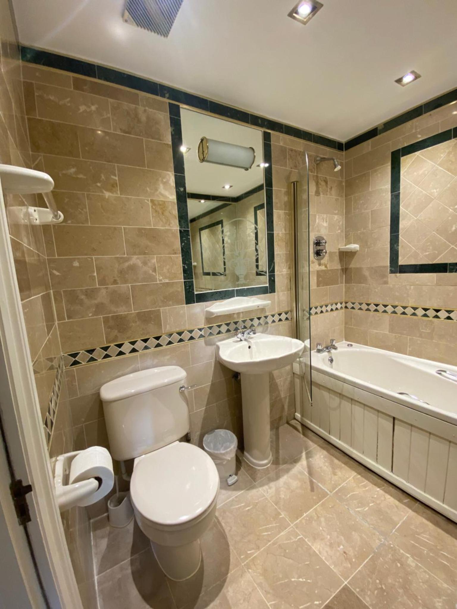 a bathroom with a toilet and a sink and a tub at The Brompton Hotel in London +58 photos