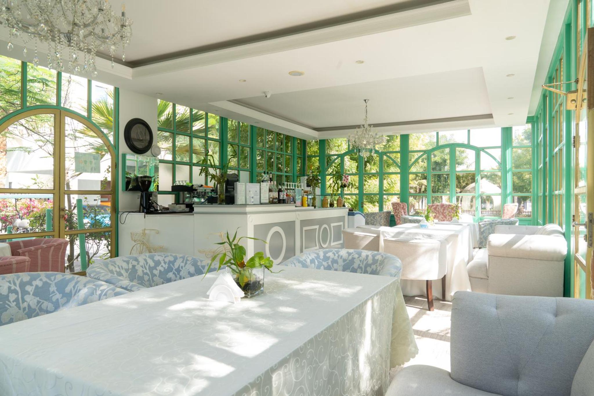 a dining room with a table and chairs and windows at Nordic Resort in Manama