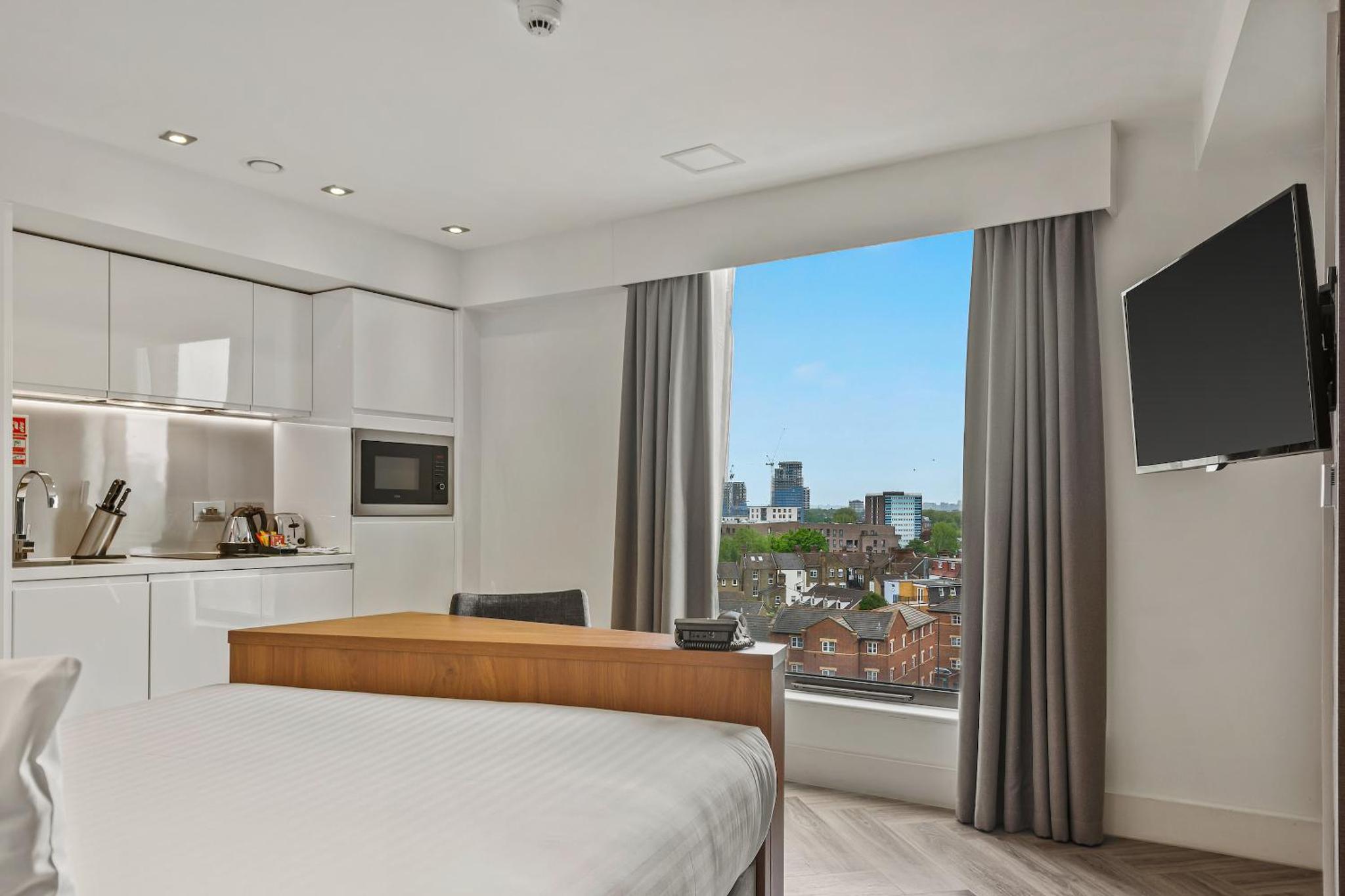 a bedroom with a bed and a large window at Roomzzz London Stratford in London