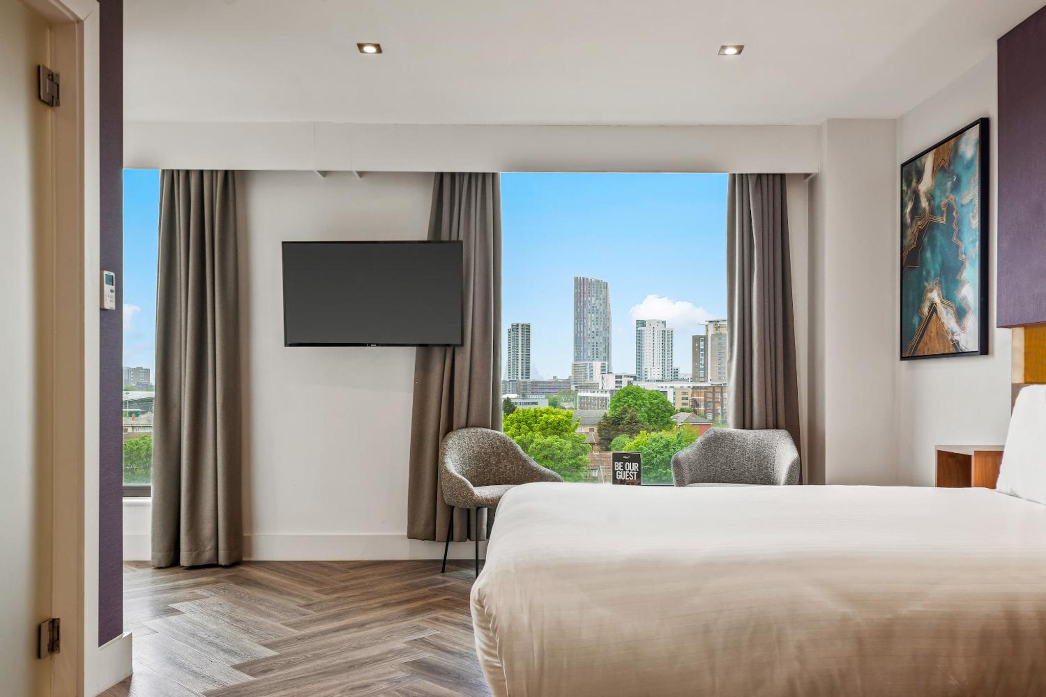 a hotel room with a bed and a large window at Roomzzz London Stratford in London