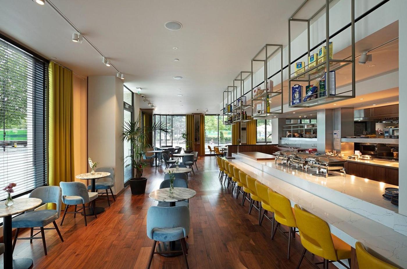 a restaurant with a bar with yellow chairs and tables at Tower Suites by Blue Orchid in London