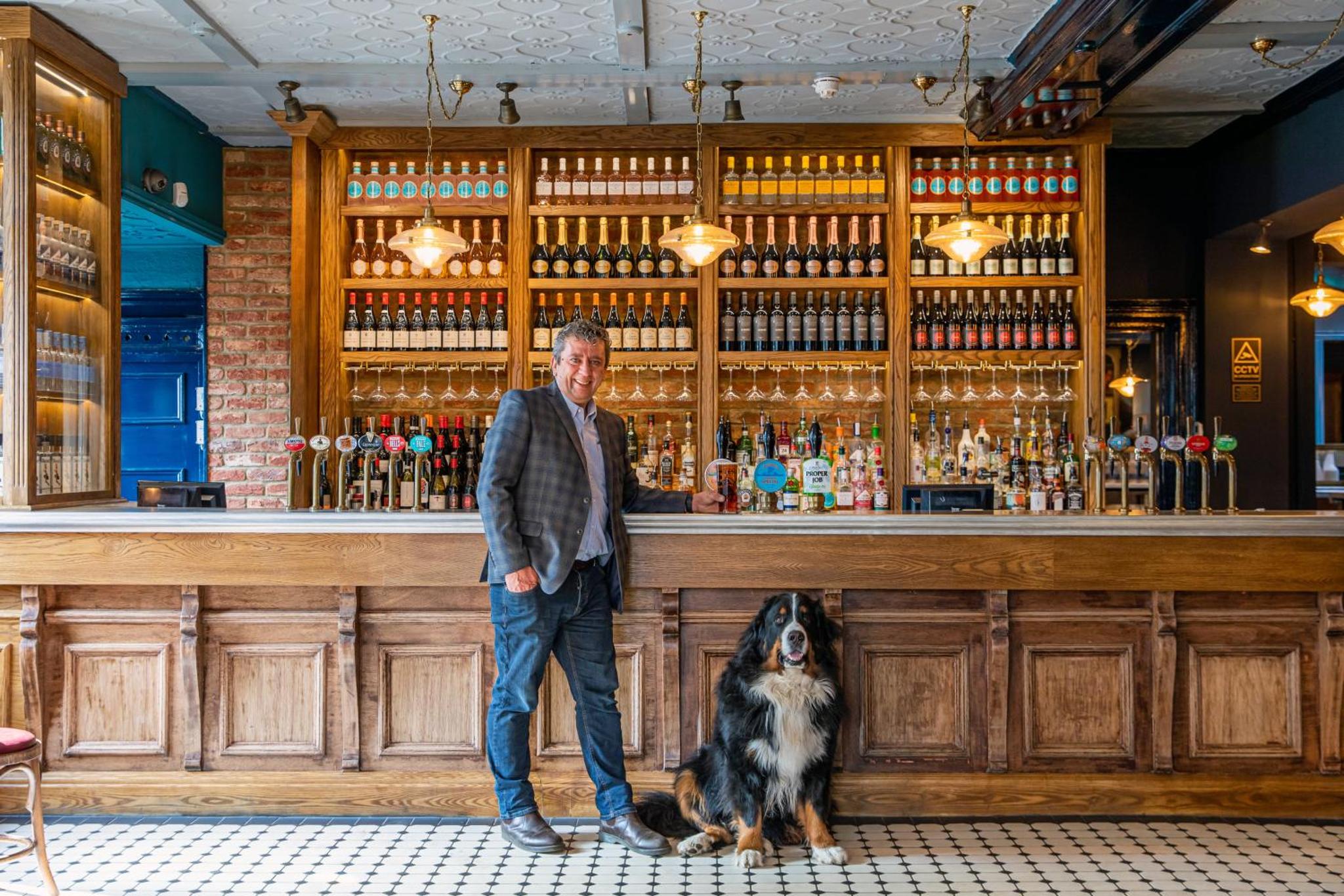 a man standing in front of a bar with a dog at The Windmill On The Common in London +21 photos