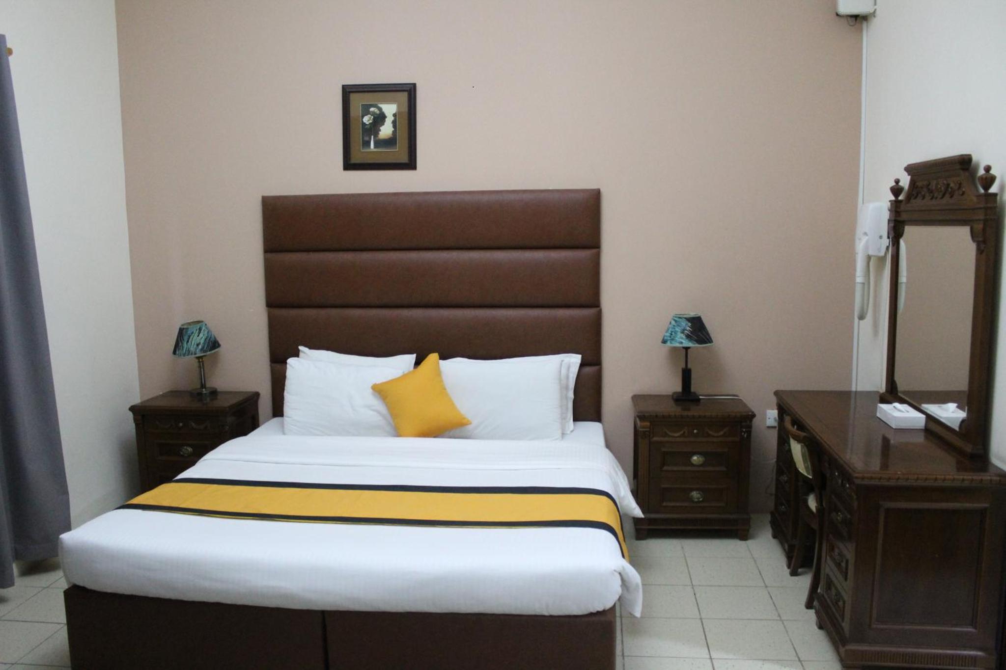 a bedroom with a large bed and two night stands at Caesar Palace in Al Ghurayfah +13 photos