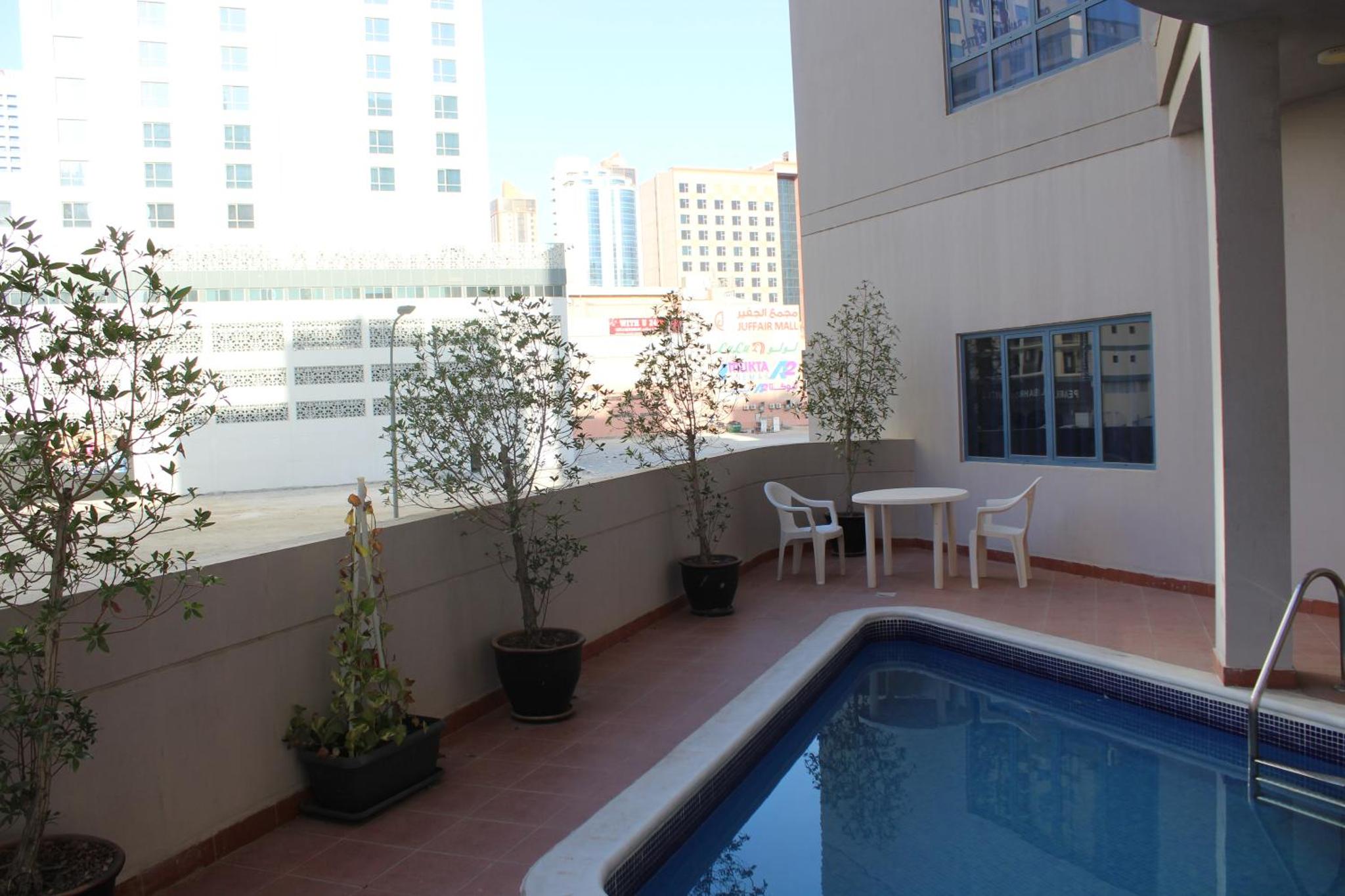 a balcony with a swimming pool and a table on a building at Caesar Palace in Al Ghurayfah