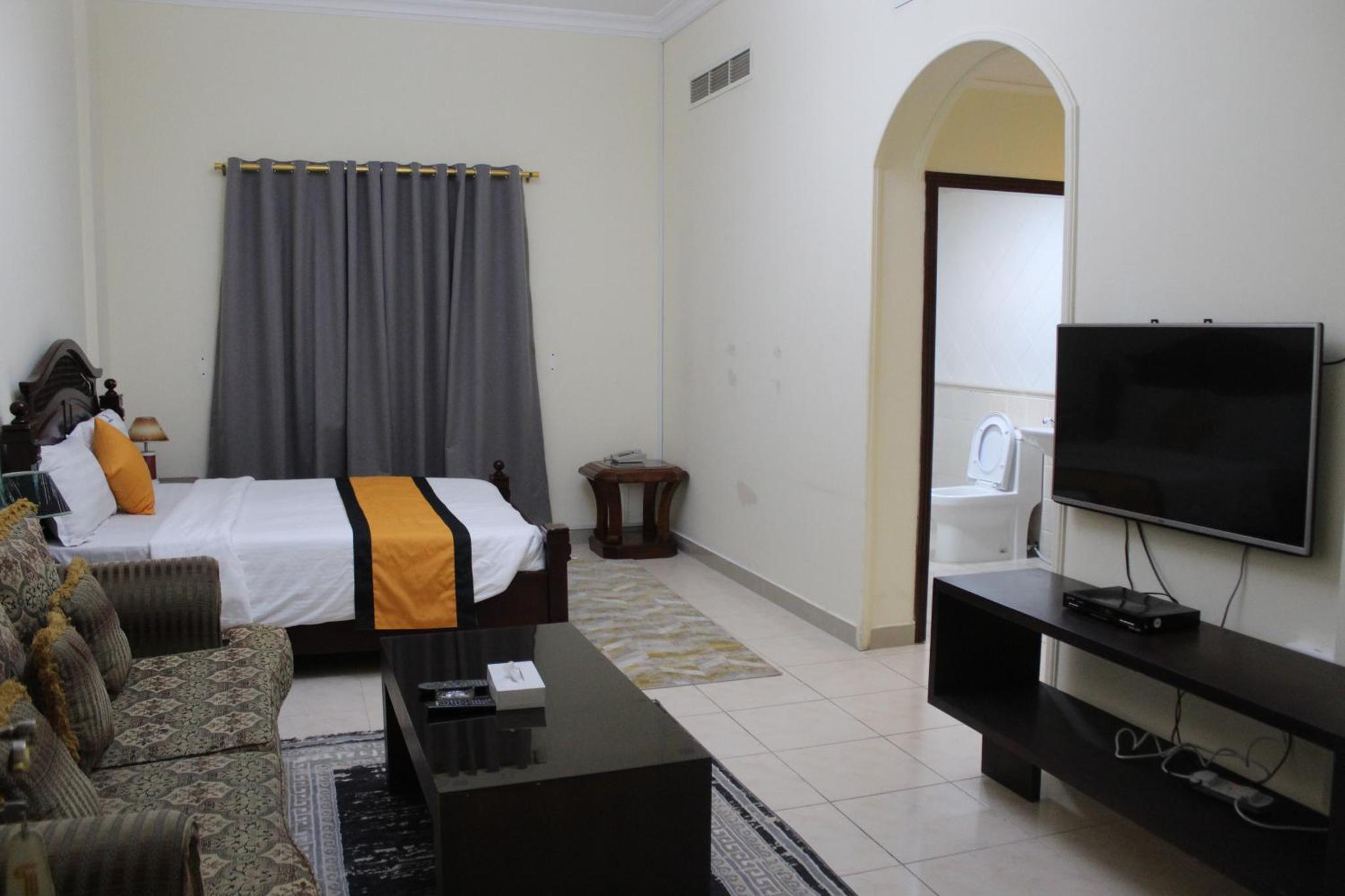 a hotel room with a bed and a flat screen tv at Caesar Palace in Al Ghurayfah