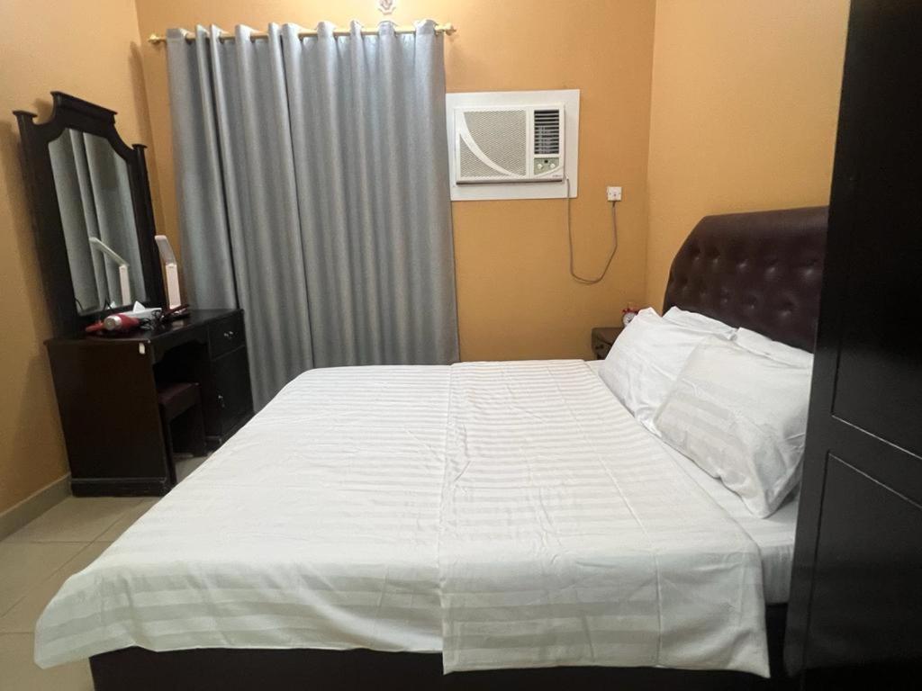 a bedroom with a bed with a white sheets and a window at Canary Islands in Manama