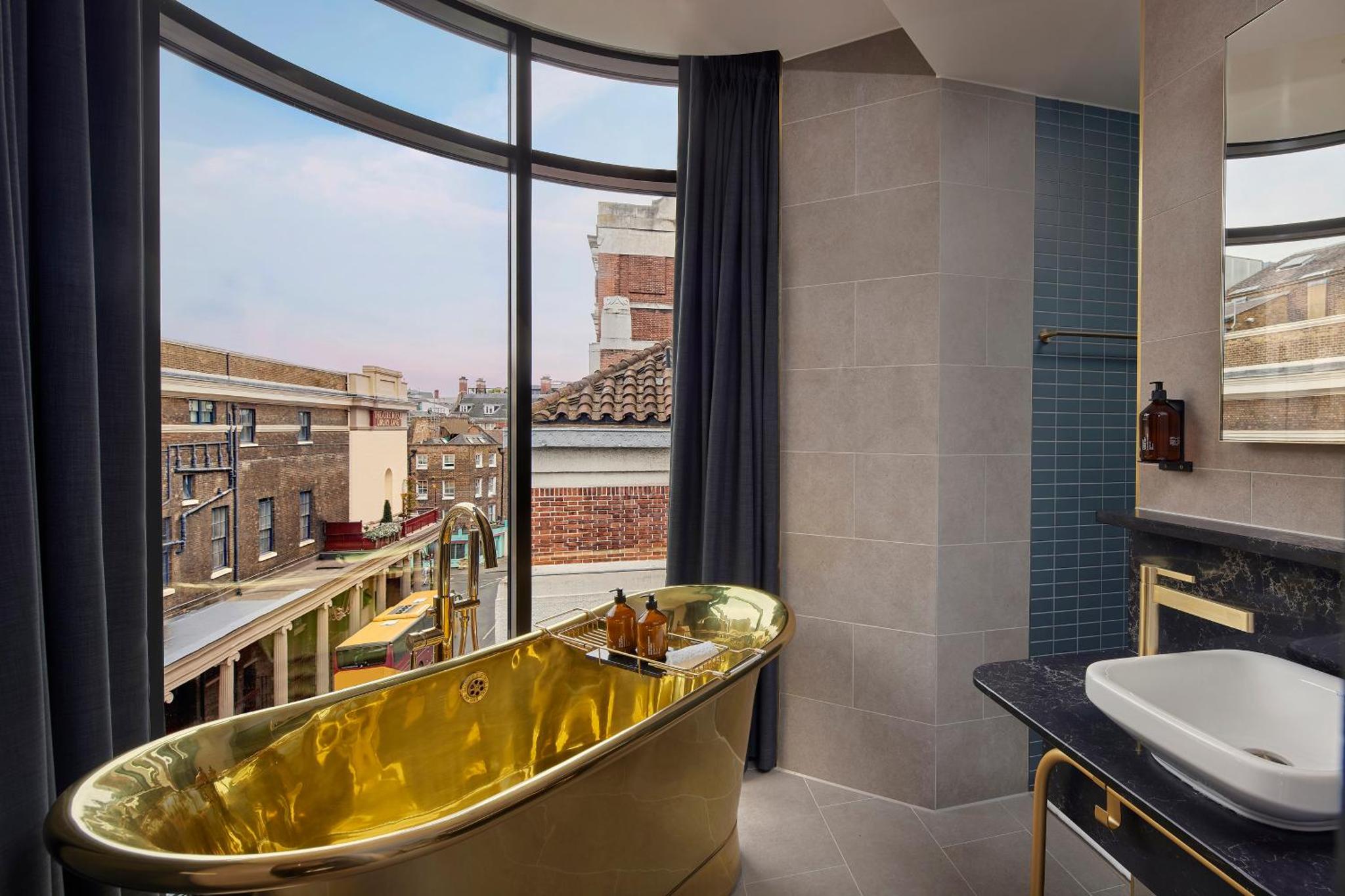 a bathroom with a tub and a large window at Hotel AMANO Covent Garden in London