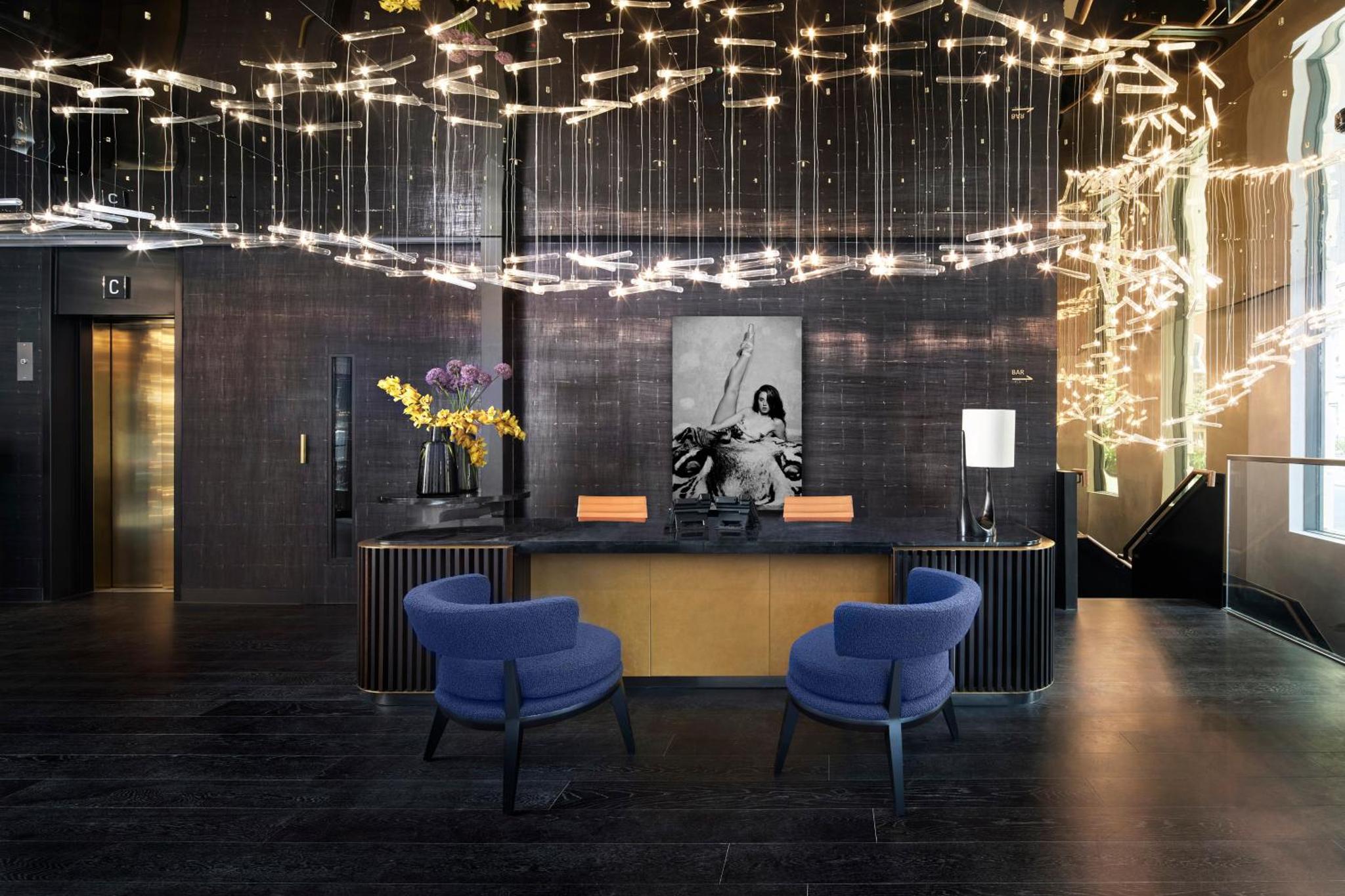 a lobby with a counter with chairs and lights at Hotel AMANO Covent Garden in London
