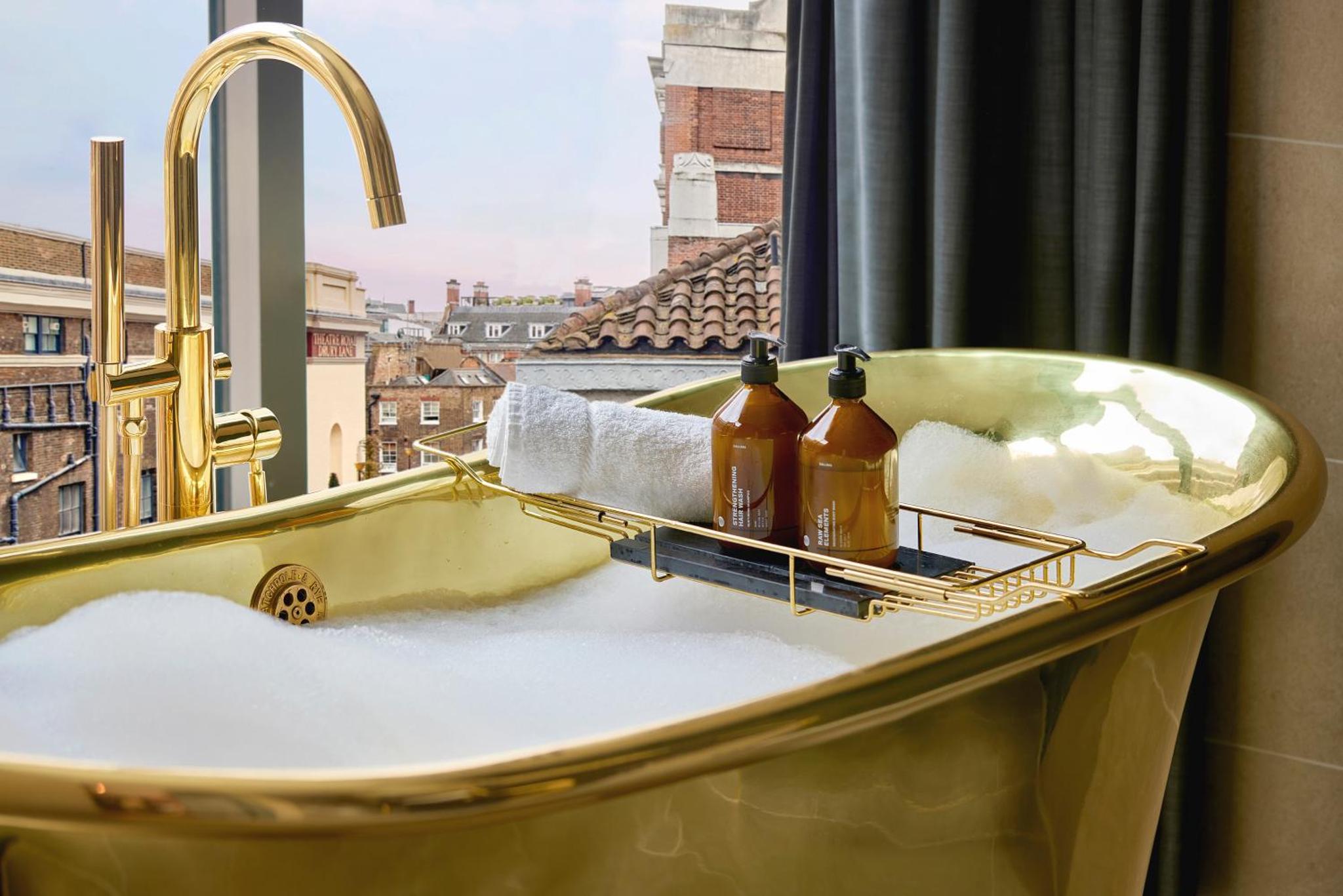 a bathroom sink with two bottles of soap and a window at Hotel AMANO Covent Garden in London +103 photos