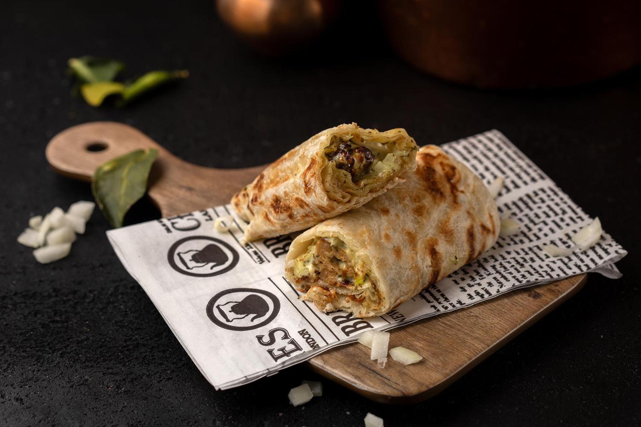 a wooden cutting board with two burritos on it at Maitrise Hotel Maida Vale - London in London +25 photos