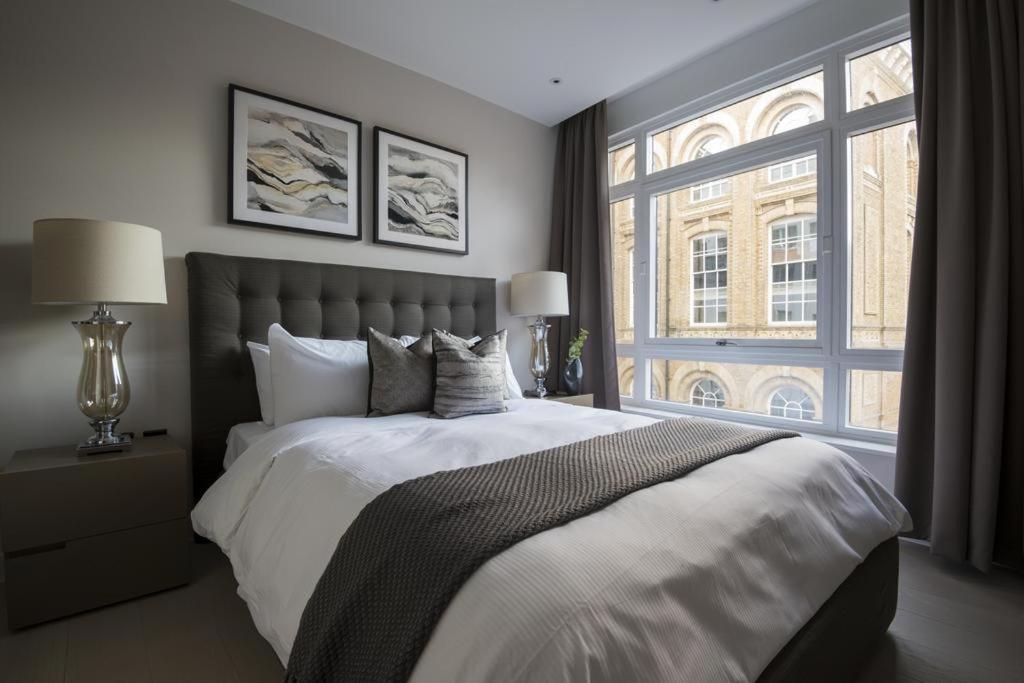 a bedroom with a large bed and a large window at Buckingham Palace Residences by Aeria Apartments in London