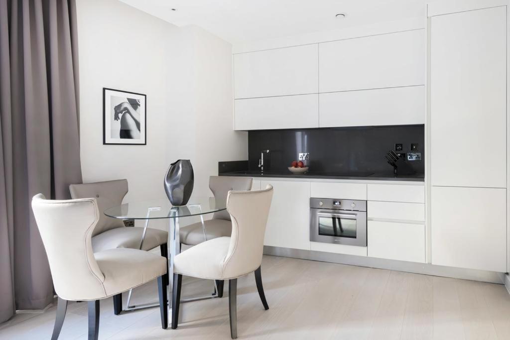 a dining room with a glass table and white chairs at Buckingham Palace Residences by Aeria Apartments in London